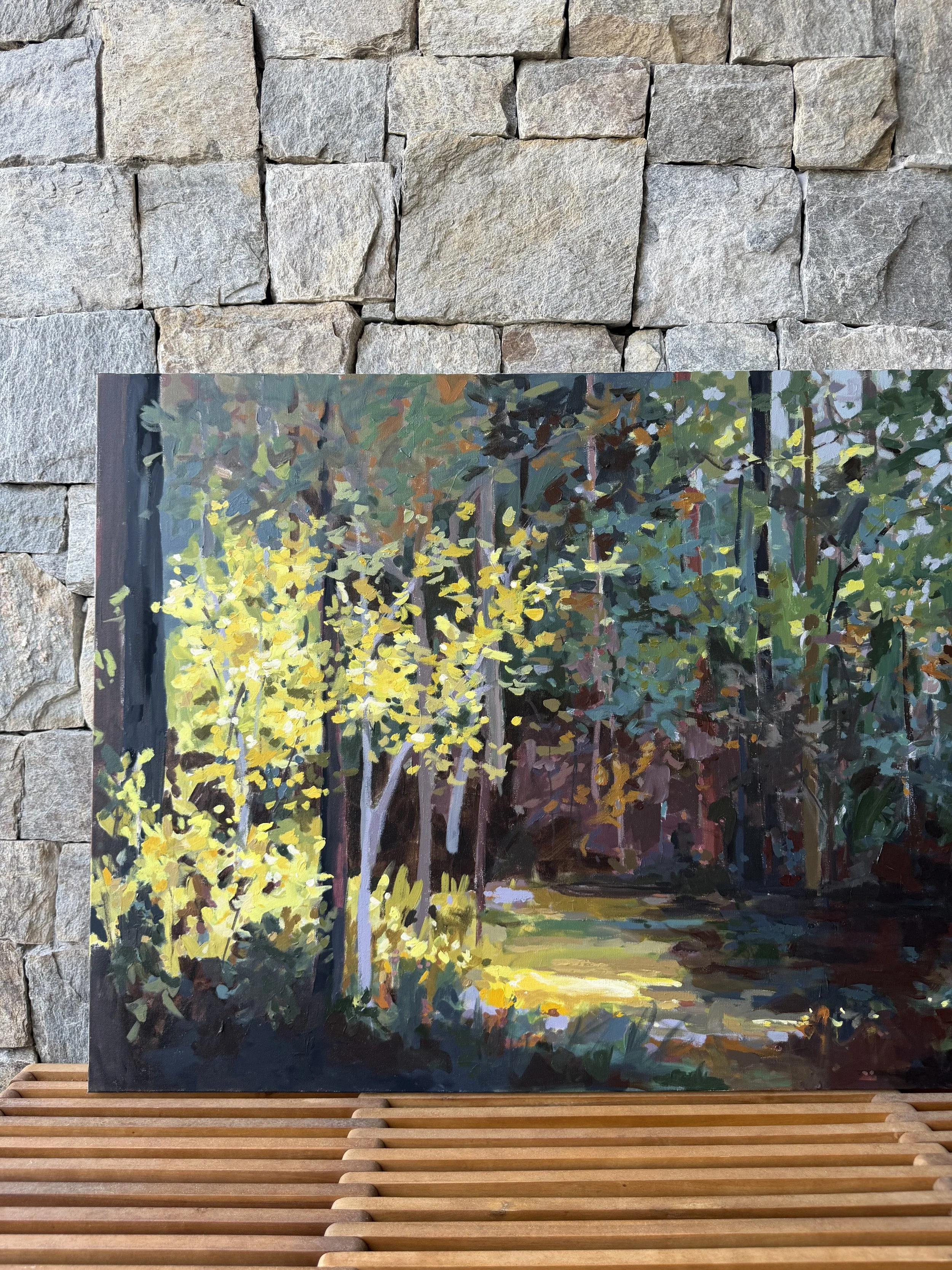 Original mixed media landscape painting by Cheyenne Trunnell displayed on a wooden bench against a stone wall, up close detail showing scale and natural light in an outdoor setting.