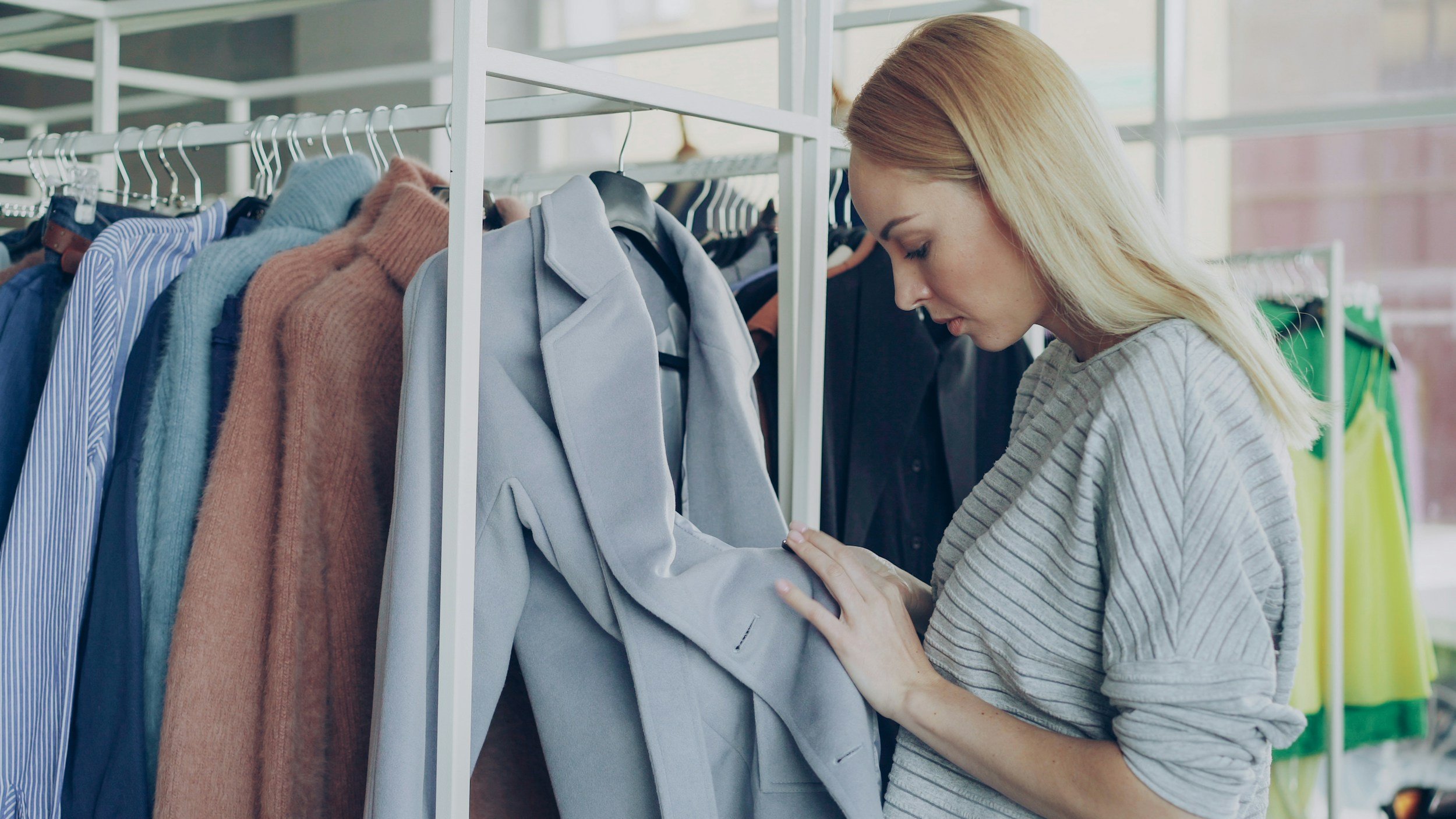 Woman inspecting a coat on a clothing rail
