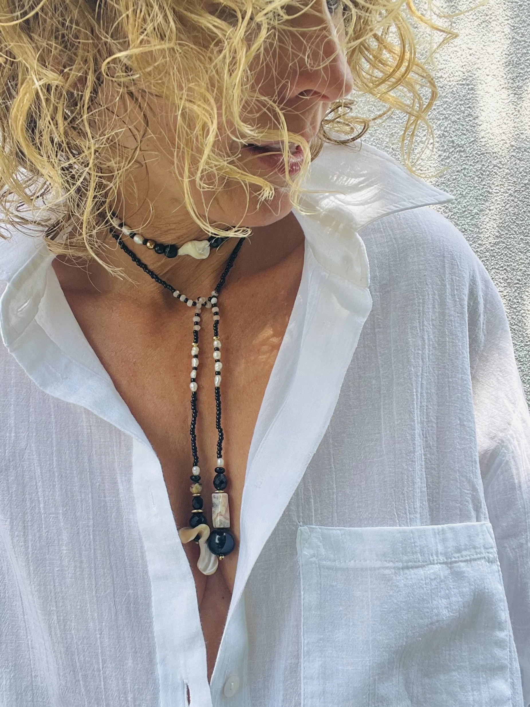 Frau trägt die Bindi Belle schwarz-beige-Muschel als lange Vintage-Kette mit Muscheln, Onyx und echten Perlen.