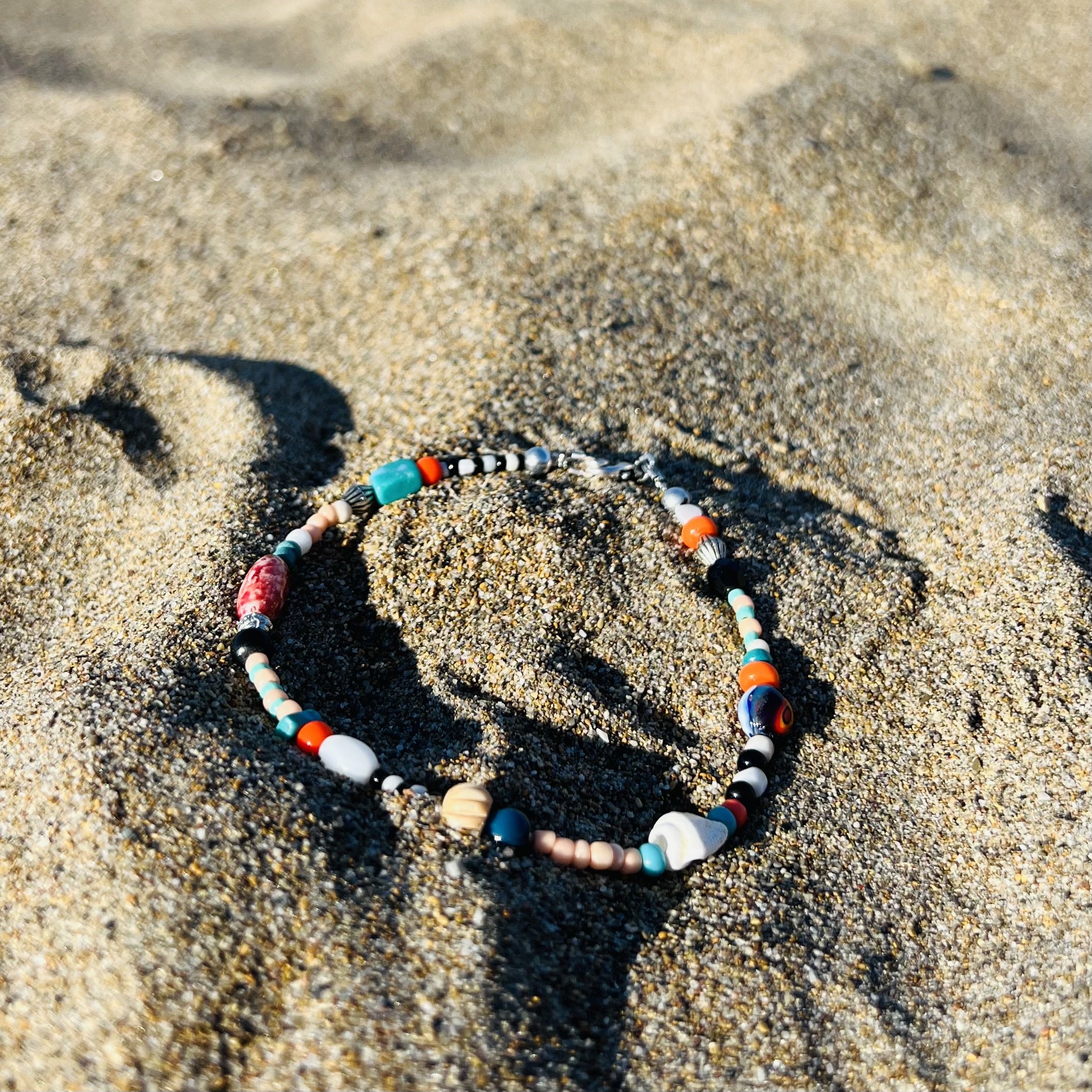 Fußkettchen auf Sand arrangiert.