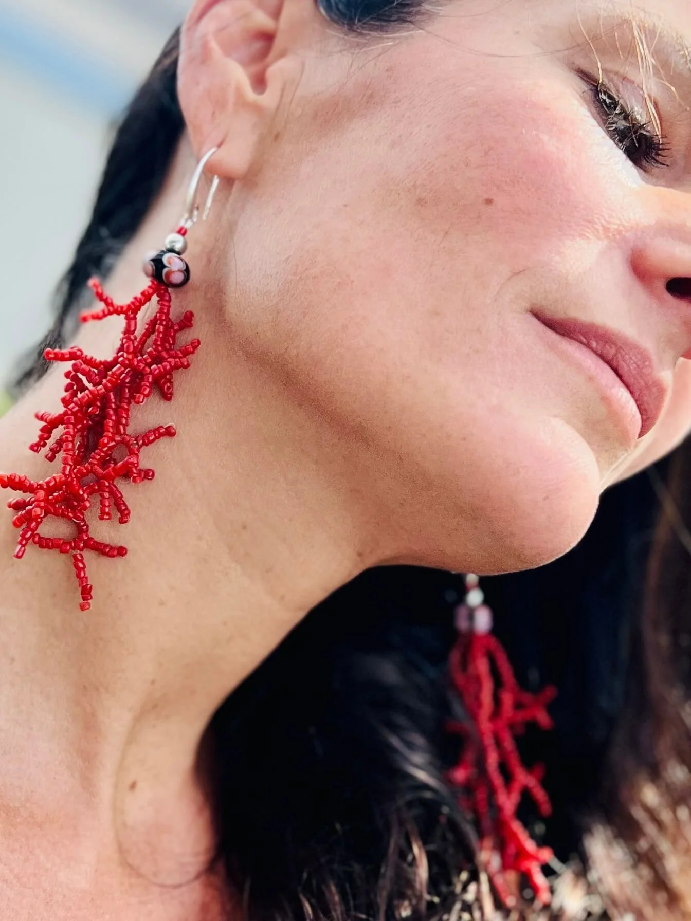 Frau mit roten Ohrringen, die wie Korallenzweige aussehen