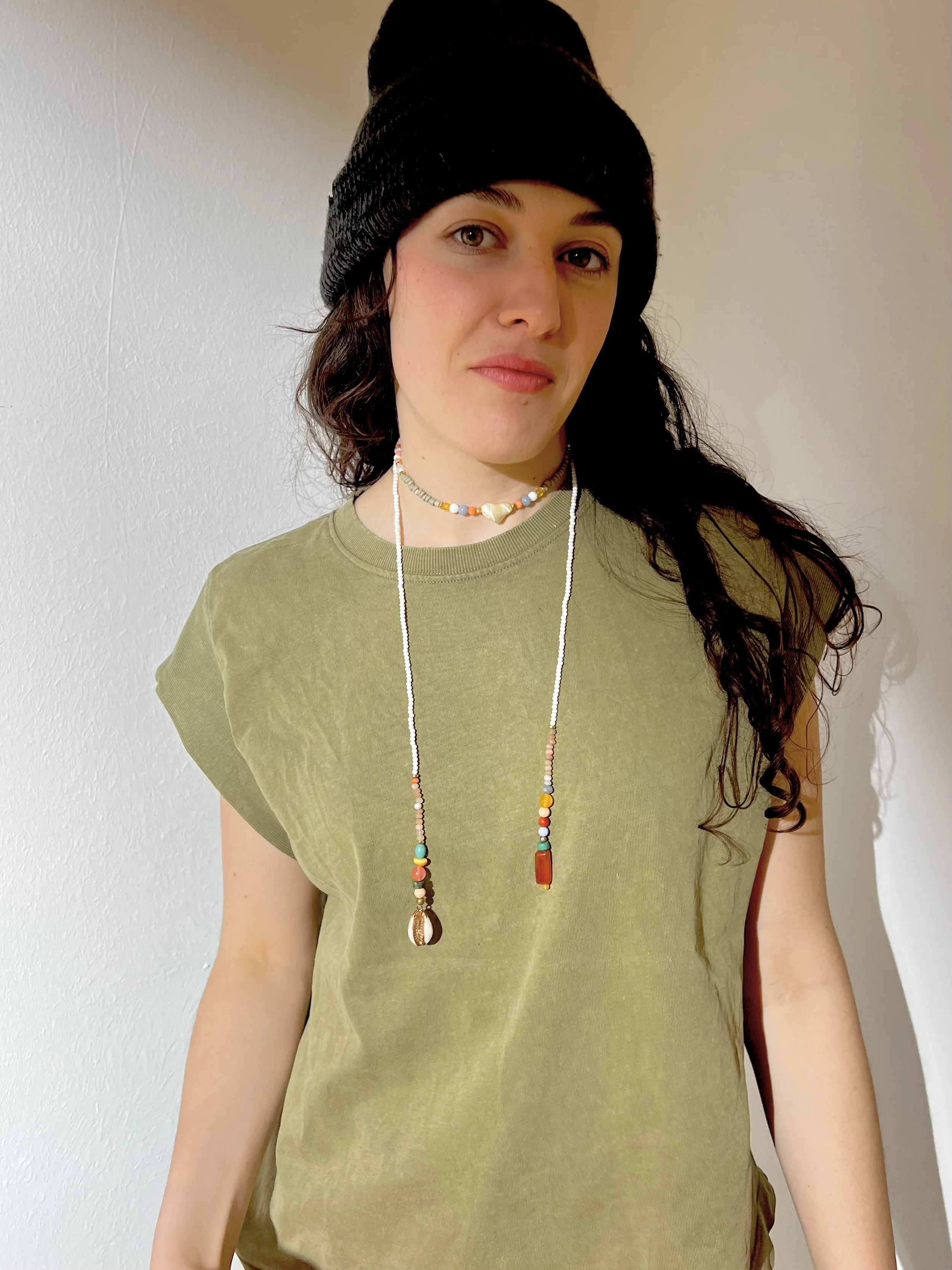 Bindi Belle Weiß-Karneol-Muschel an jungem Model mit grüner Bluse und sichtbaren Muschelanhängern