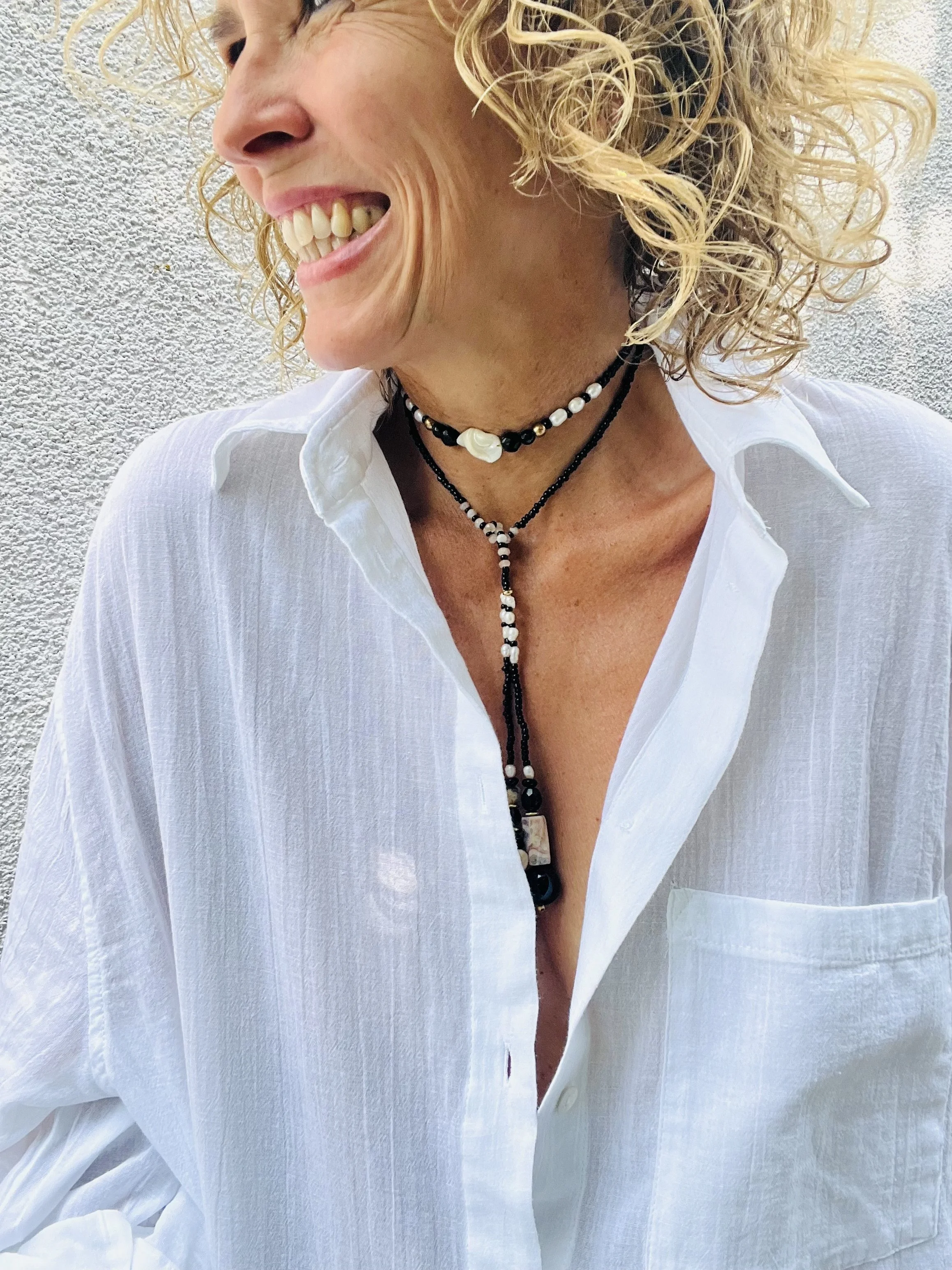 Frau trägt die Bindi Belle schwarz-beige-Muschel im Sonnenlicht.