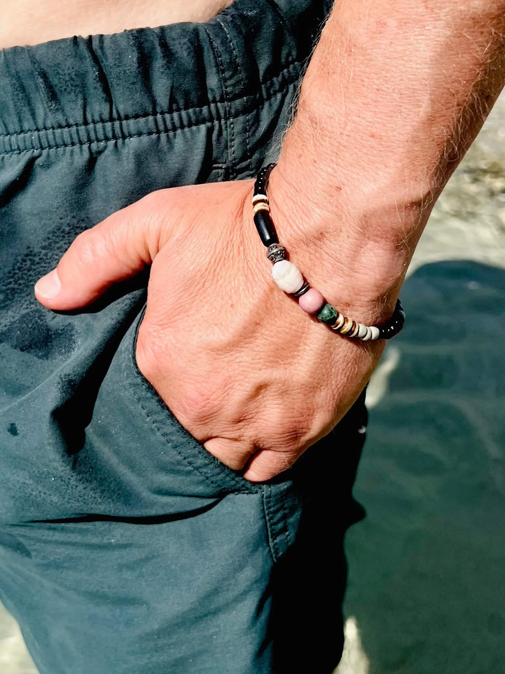 Männerhand am Strand mit Armband von Frohlotte