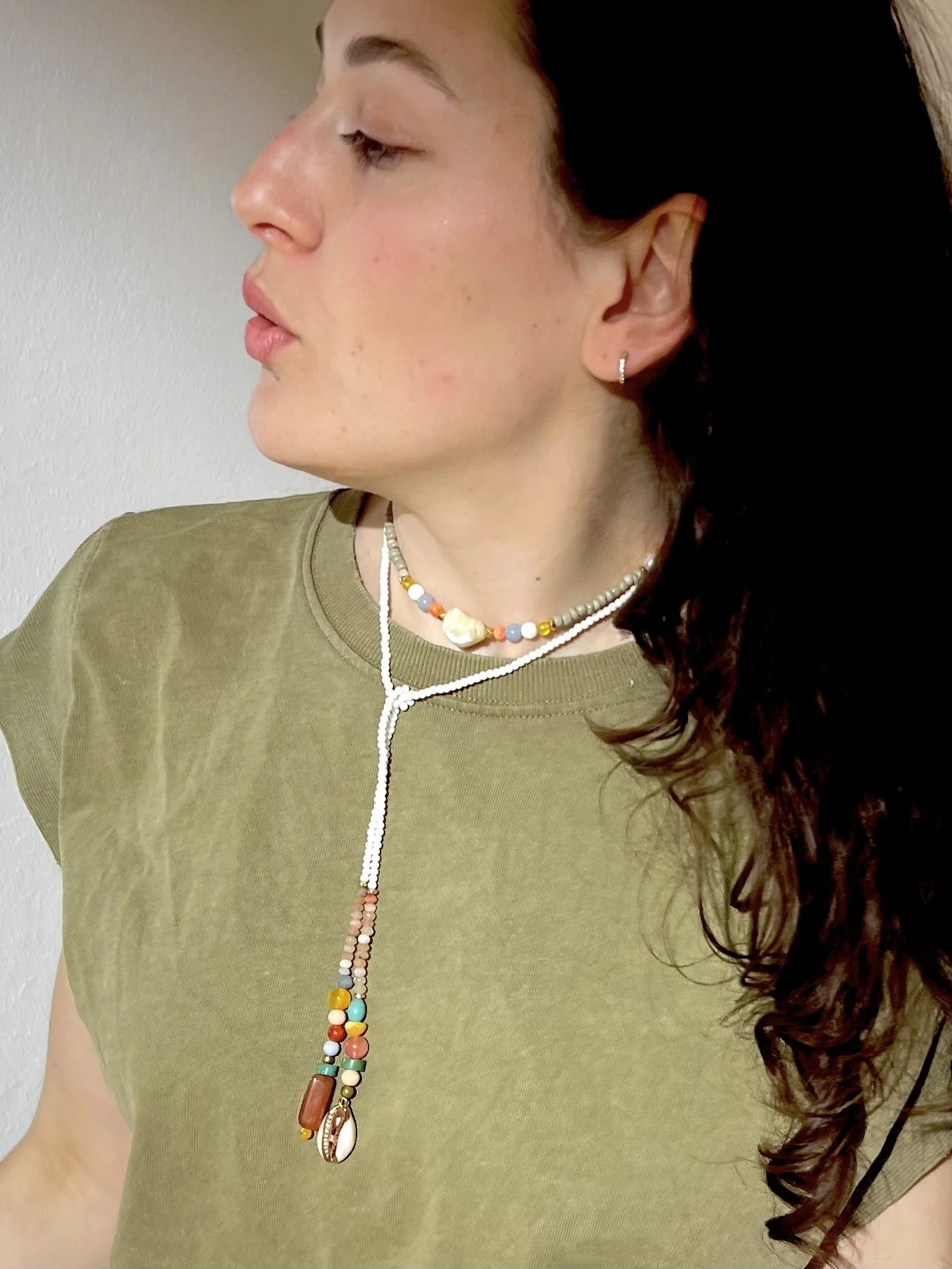Junge Frau trägt Bindi Belle Weiß-Karneol-Muschel als lange Wickelkette zu grünem Oberteil