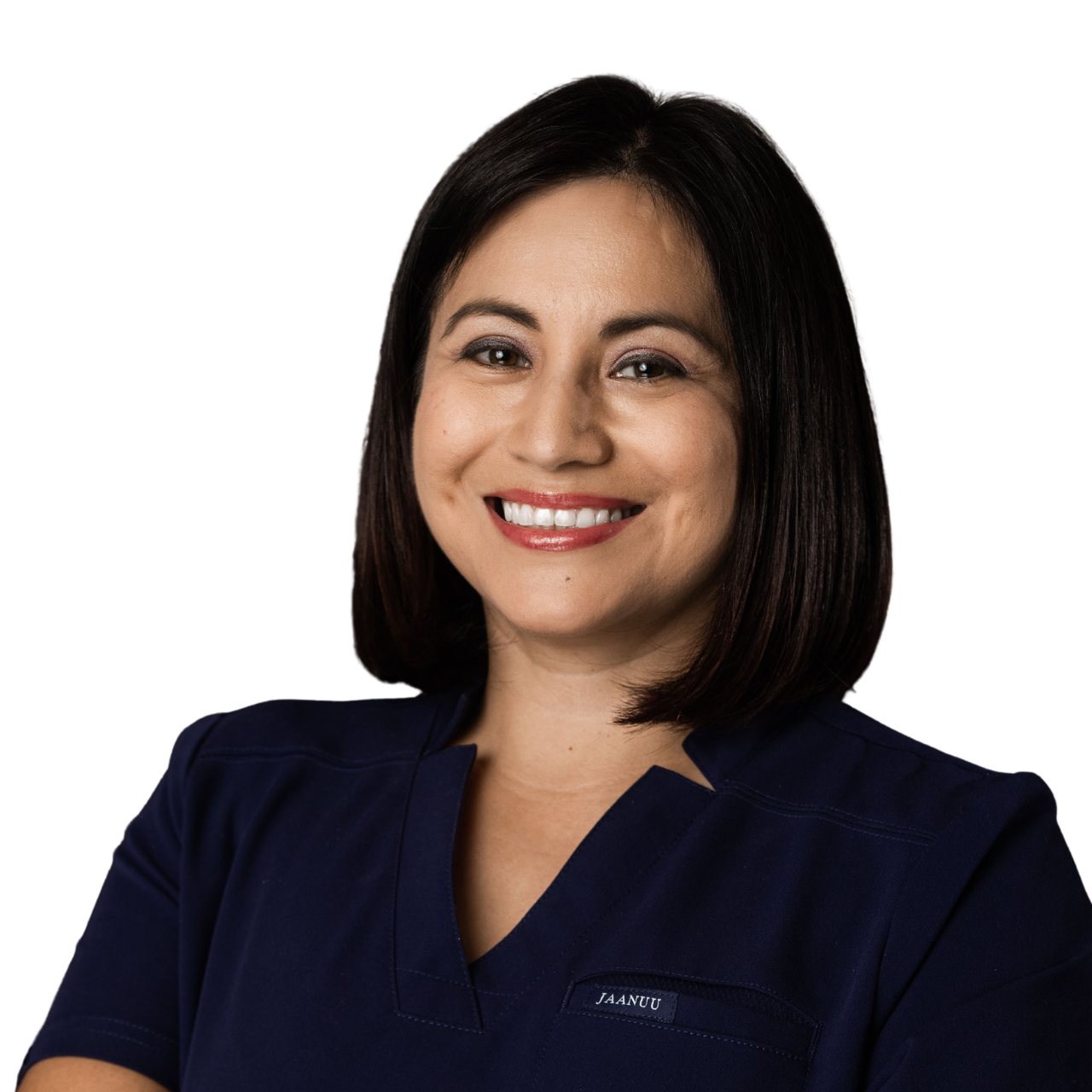 A woman with shoulder-length black hair smiling, wearing a navy blue uniform with a name tag that says 'JAANUU', her arms crossed, standing against a blurred indoor background.