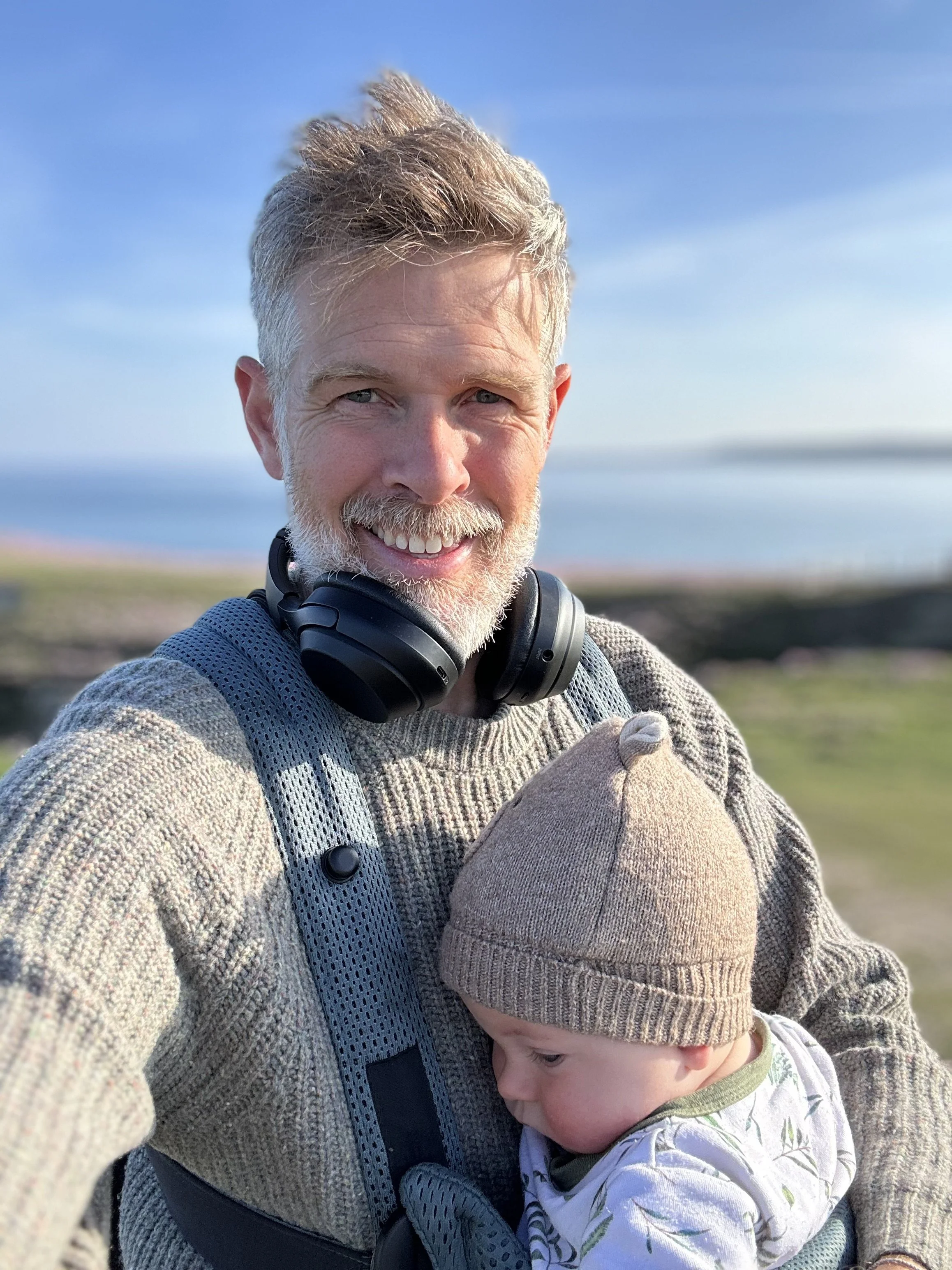 Olly Carter holding son Bear on sunny Cornish clifftops, dad reclaiming spark through family play