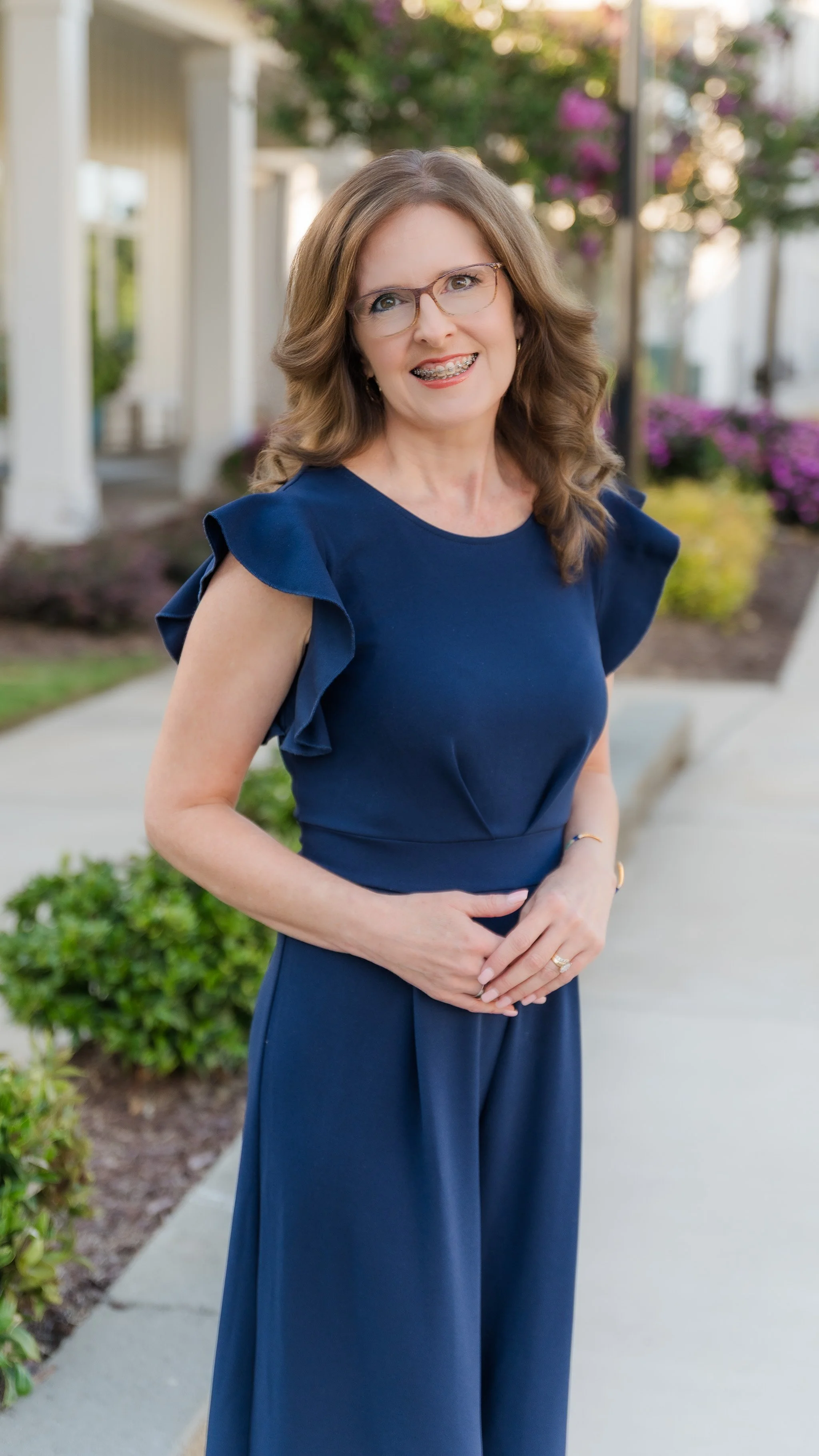 Headshot of a woman with brown hair wearing a navy blue romper posing for professional portrait