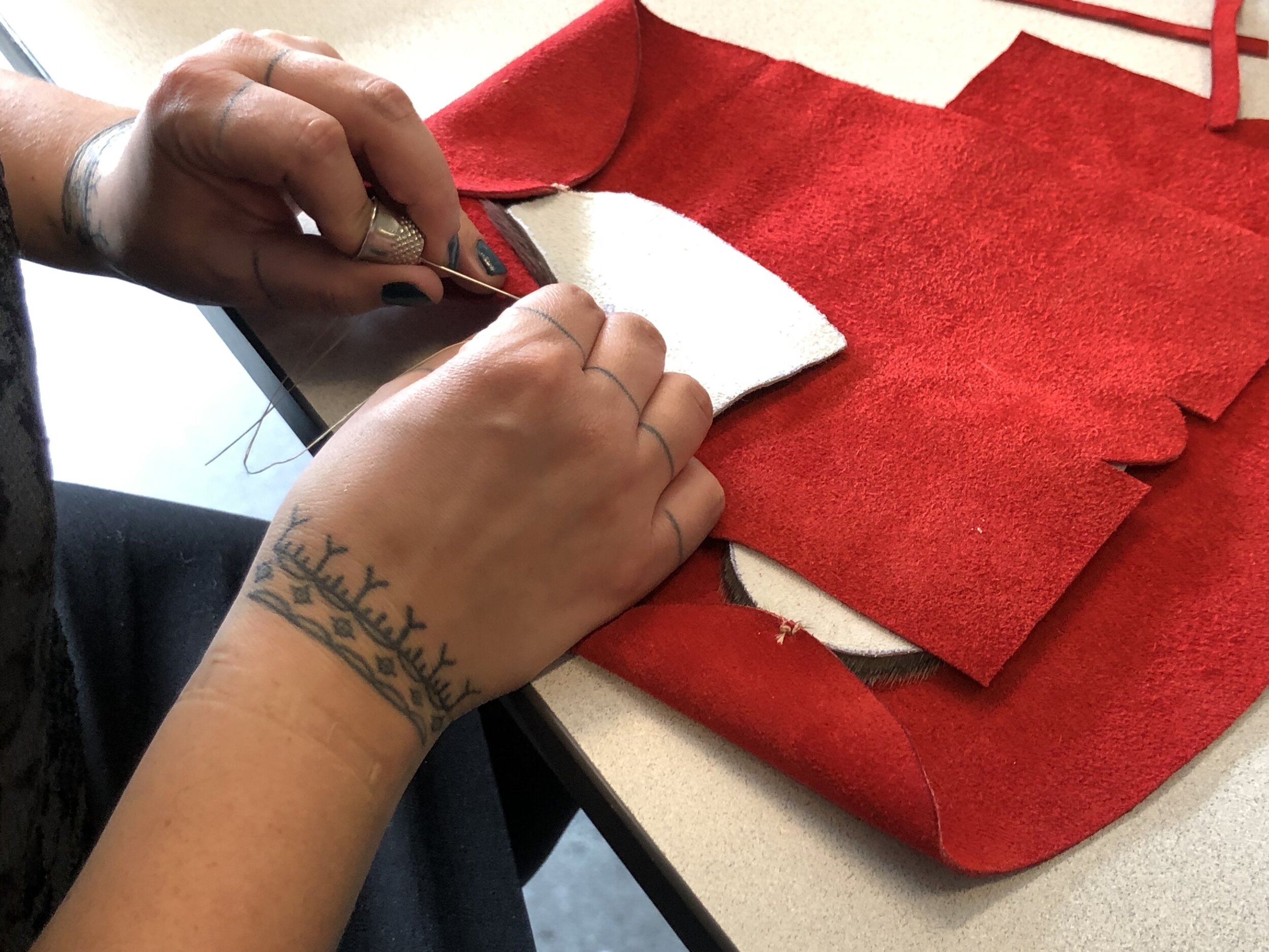  Heather Igloliorte sewing her pair of slippers at the Labrador Inuit Slipper Making Workshop, led by Veronica Flowers and Vanessa Flowers. This session was held at Concordia University, Montreal QC, October 2019. Photo courtesy of Heather Igloliorte