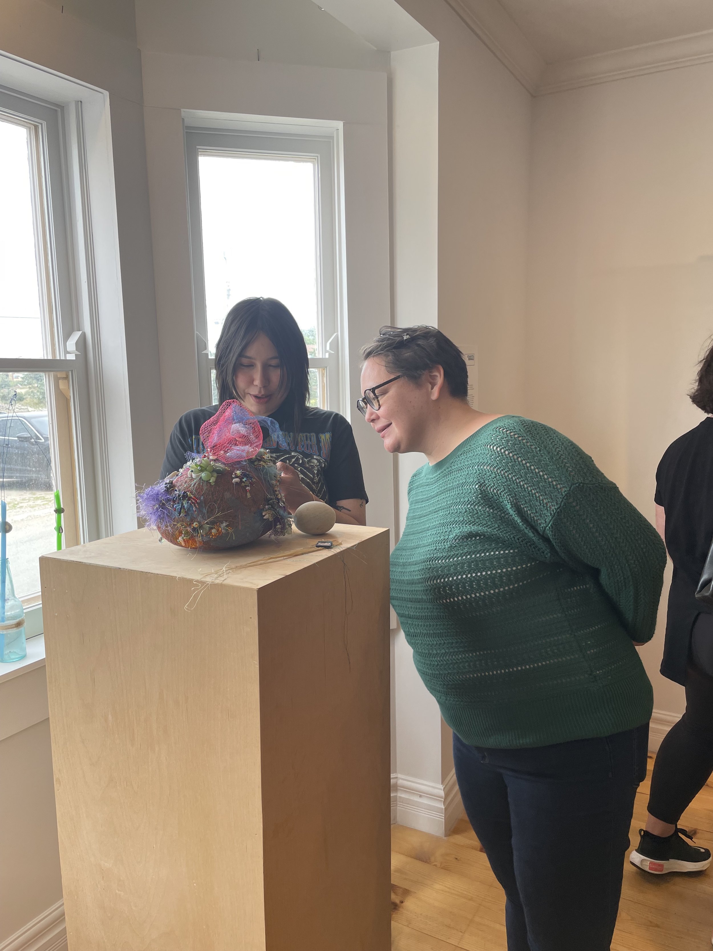  Ilinniaqtuit alumni Leanne Unuarak-Dall and Napatsi Folger look at Shirley Moorhouse’s sculpture during the Bonavista Biennale, August 2023. Bonavista, NL. Photograph by Danielle Miles. 