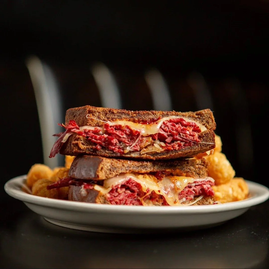 Have you had the joy of biting into one of our Reubens? 🤤 

Thick slabs of corned beef, cooked slow, falling apart like your sorry life. Sauerkraut, tangy as hell, slapped on like it owes you money. Swiss cheese with holes like your goddamn logic. M