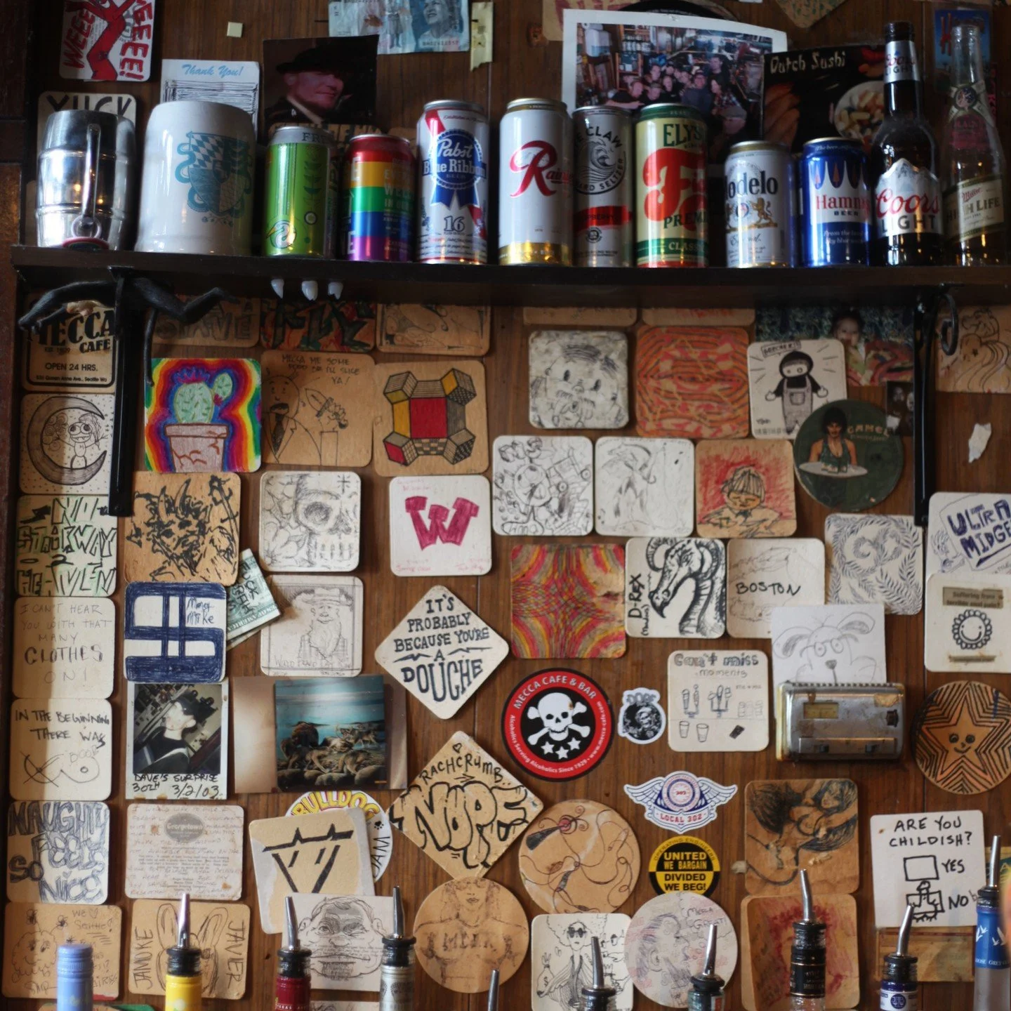 Coaster Wall > Gum Wall. 

Duck into the bar at Mecca and take in one of Seattle's great local exhibits without touching a stranger's spit.

You'll get to enjoy a frosty beverage while you critique artists of bygone, happy hours.
Mecca is home to 