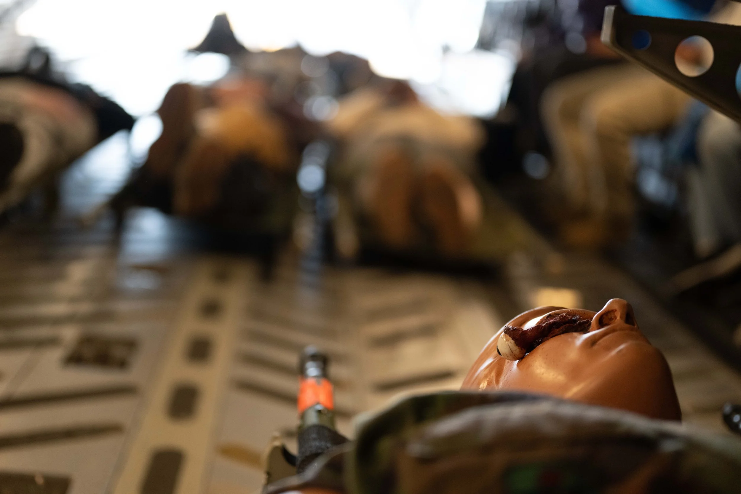 A close-up of a human-like face sculpture with a snail on its head, in a storage or warehouse setting with more sculptures in the background.