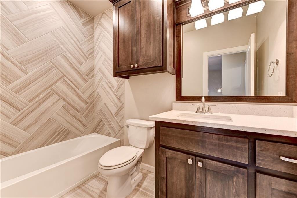 guest bathroom herringbone tile pattern custom stained cabinets quartz countertop.JPG