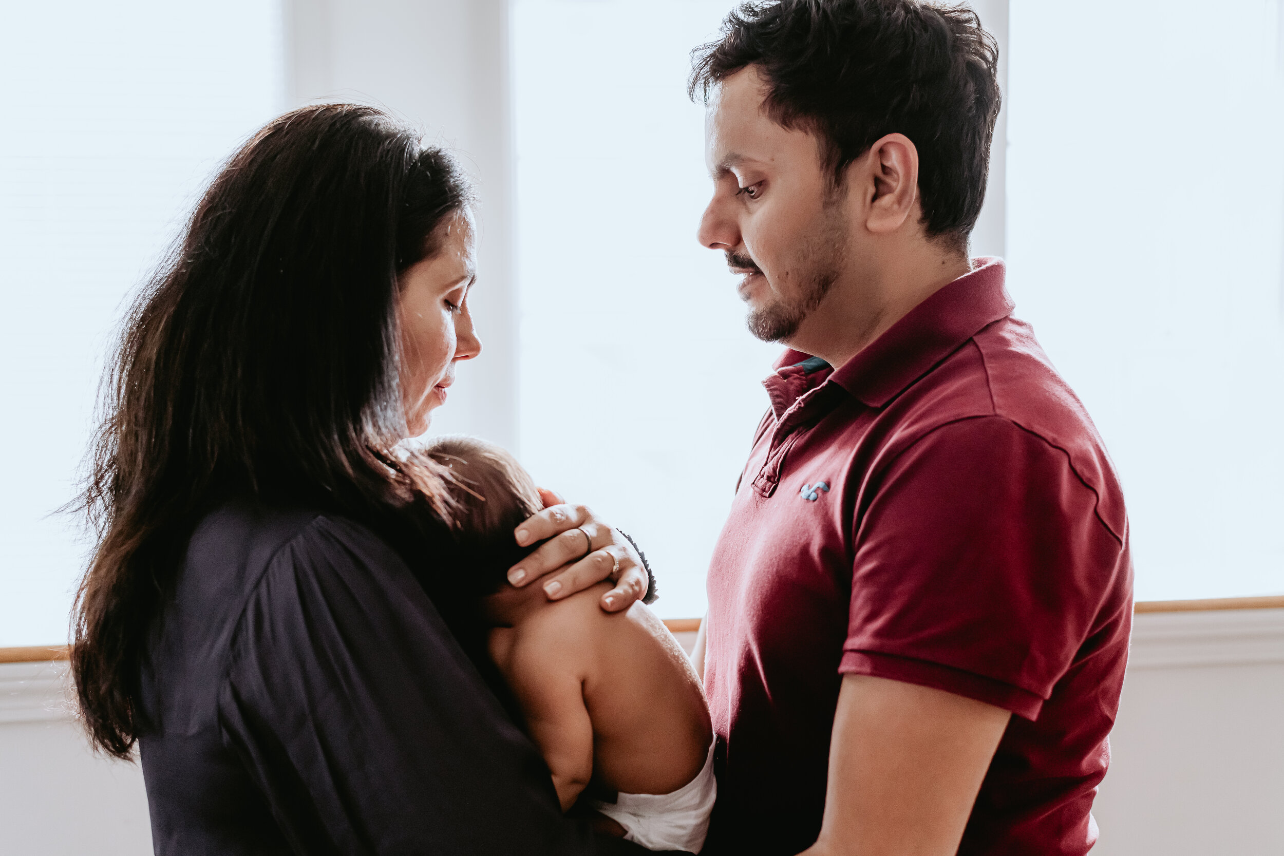  Connecticut Lifestyle Newborn Portrait - Mom and Dad holding son in front a beautiful window light 