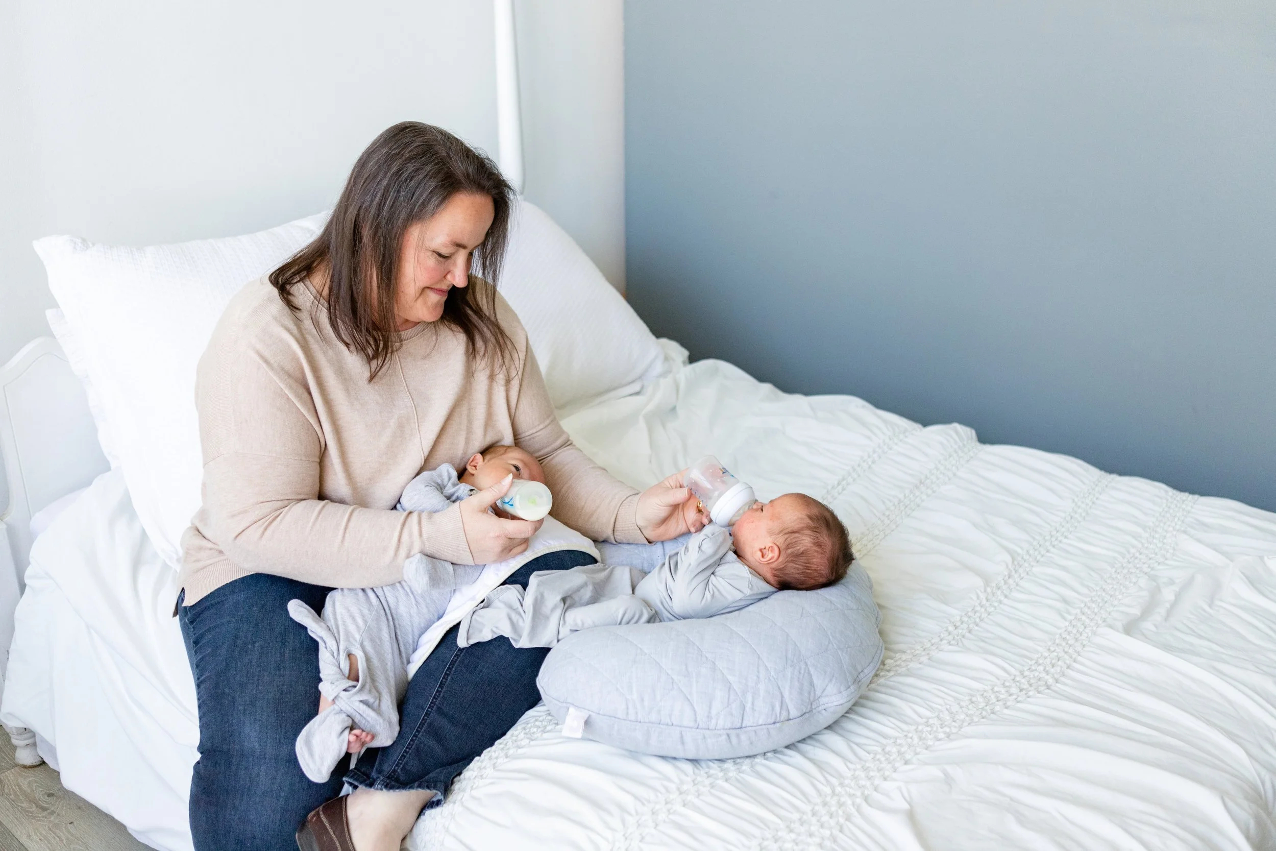 Postpartum doula in Utah feeding newborn twins, offering care through The Baby Hive agency