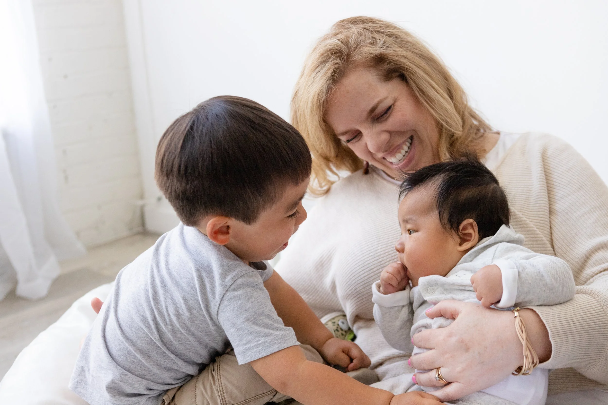 A Utah babysitter and night nanny, who specializes in newborn care, laughs while playing with a baby and young child.