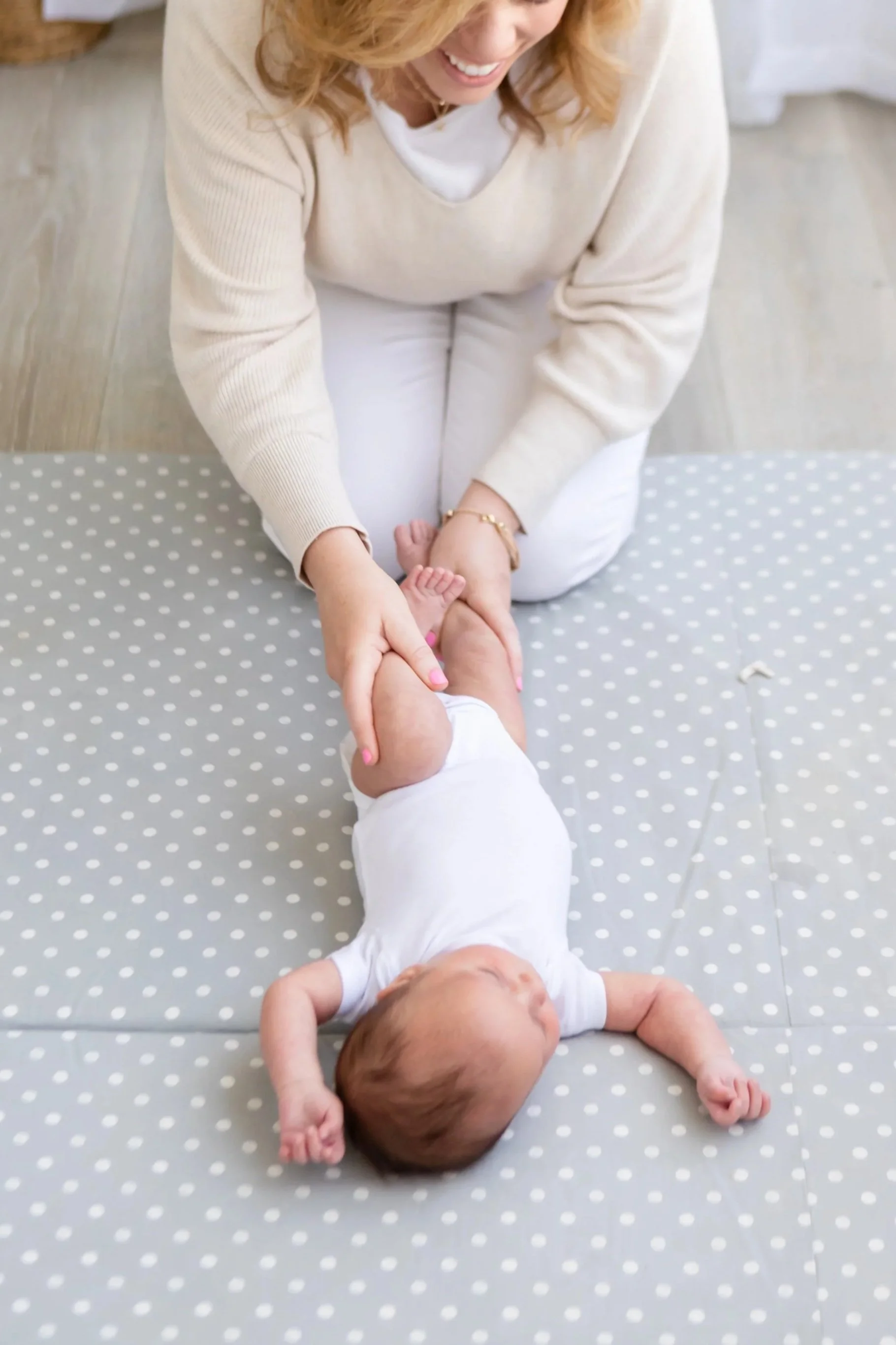 A postpartum doula and newborn care specialist holds a newborns legs during play time in Salt Lake City, Utah.