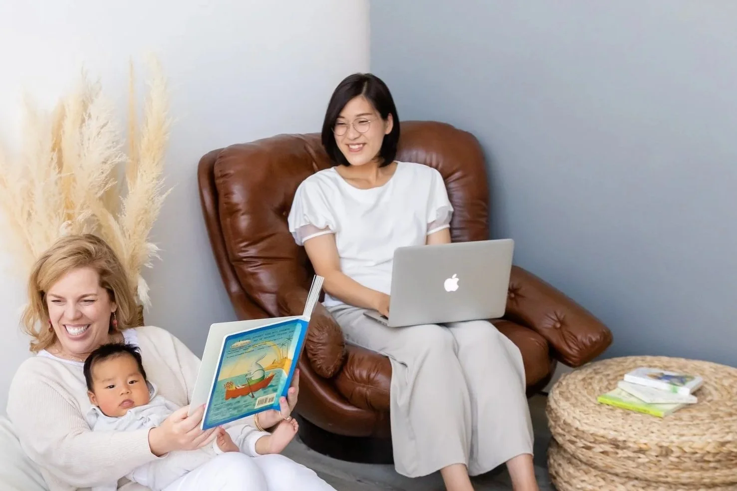 A mom types at her laptop and smiles at her night nanny, who she hired to help her family with newborn overnight care in Park City, Utah.