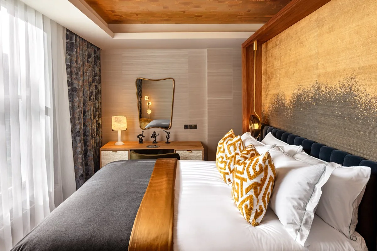 Principal bedroom with upholstered headboard, layered textiles and bespoke wall finish.