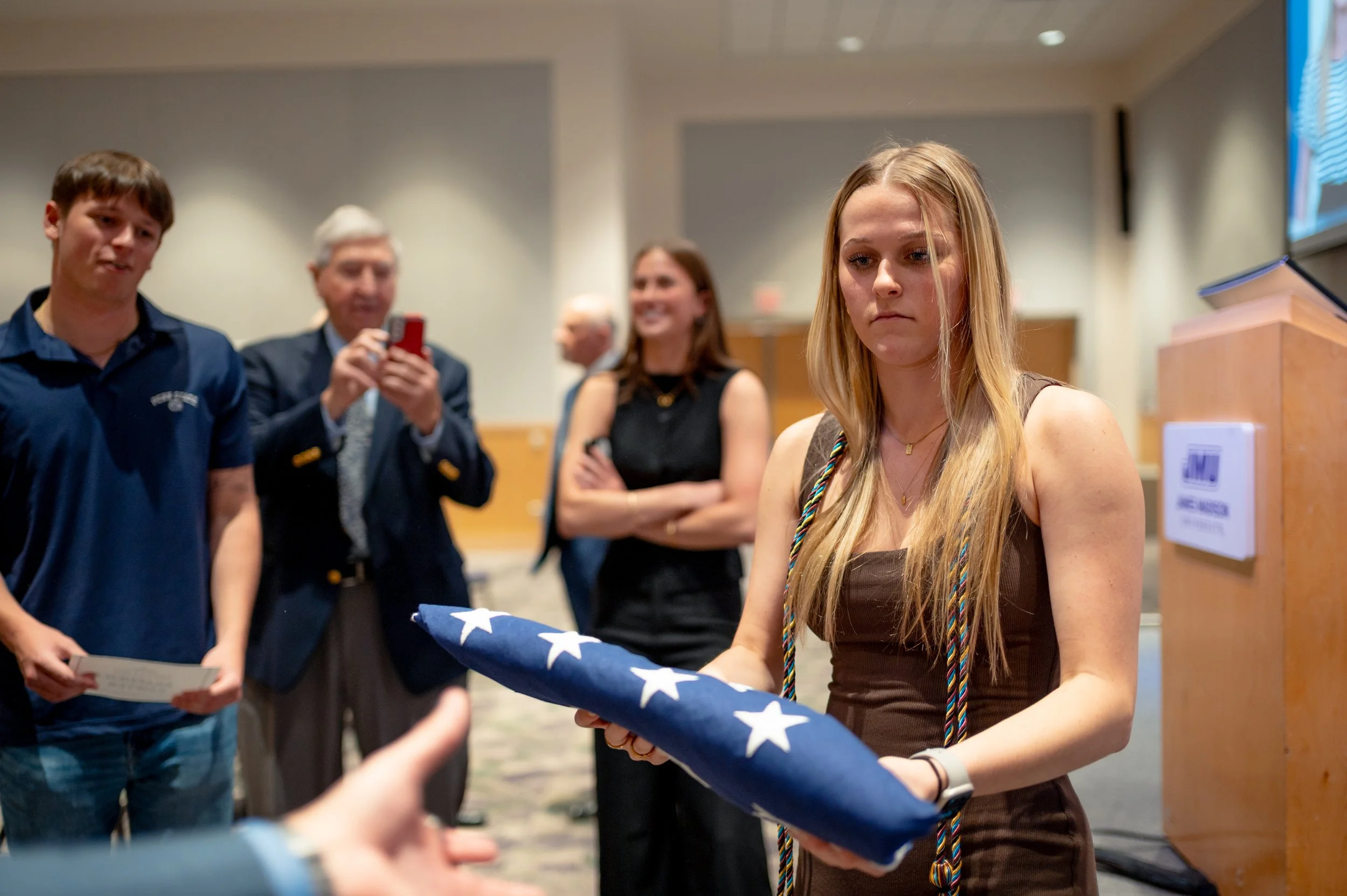  Former Chief White House Producer and Deputy Chief of Staff Grace L. Sawyer hands an aide a flag that was flown over the United States Capitol Building on Sawyer’s last day at the White House on January 25, 2026 after a surprise award ceremony honor