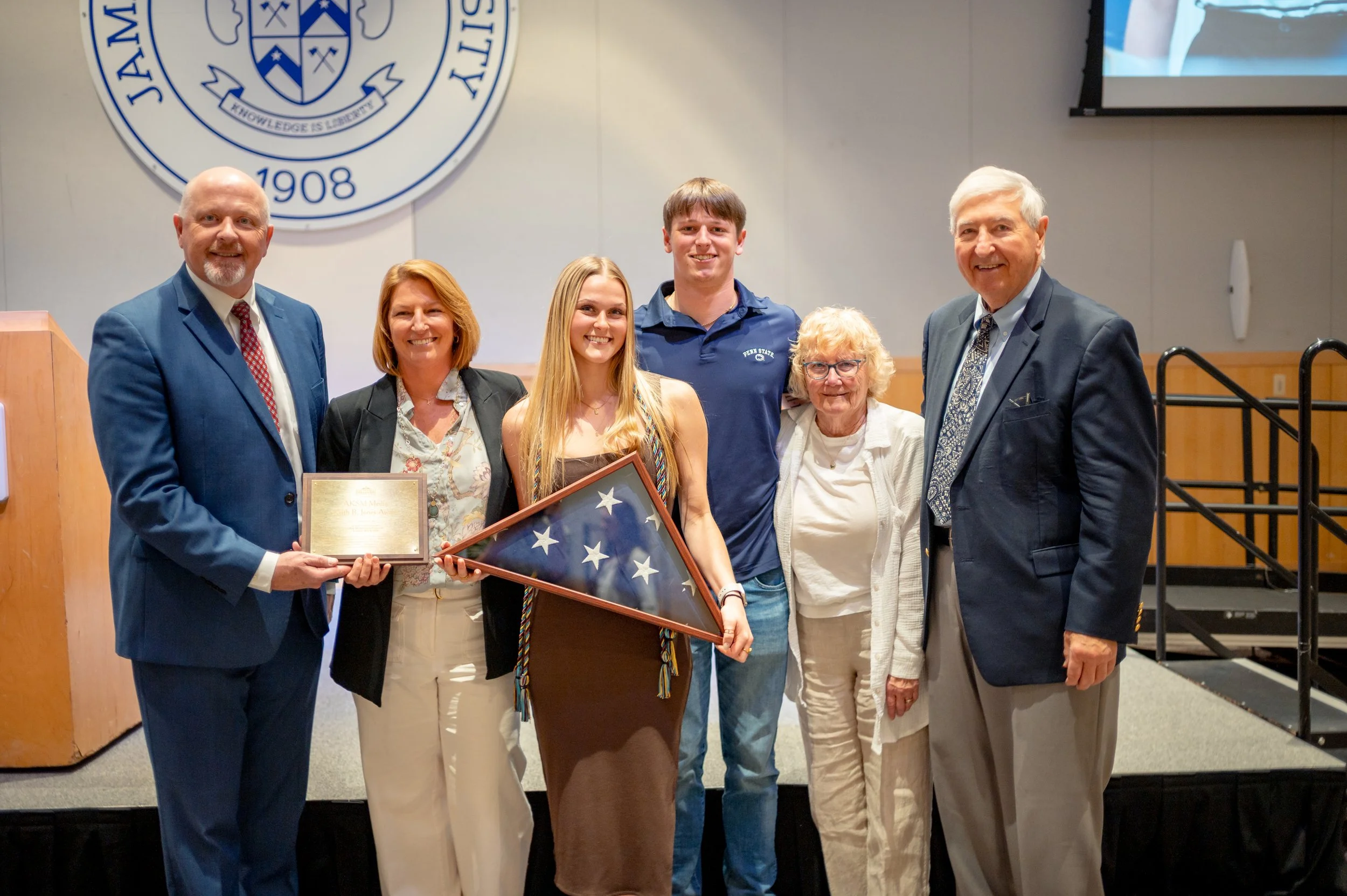  Former Chief White House Producer and Deputy Chief of Staff Grace L. Sawyer poses for a family photo with the 2026 Keith B. Jones Award and a flag that was flown over the United States Capitol Building on Sawyer’s last day at the White House on Janu