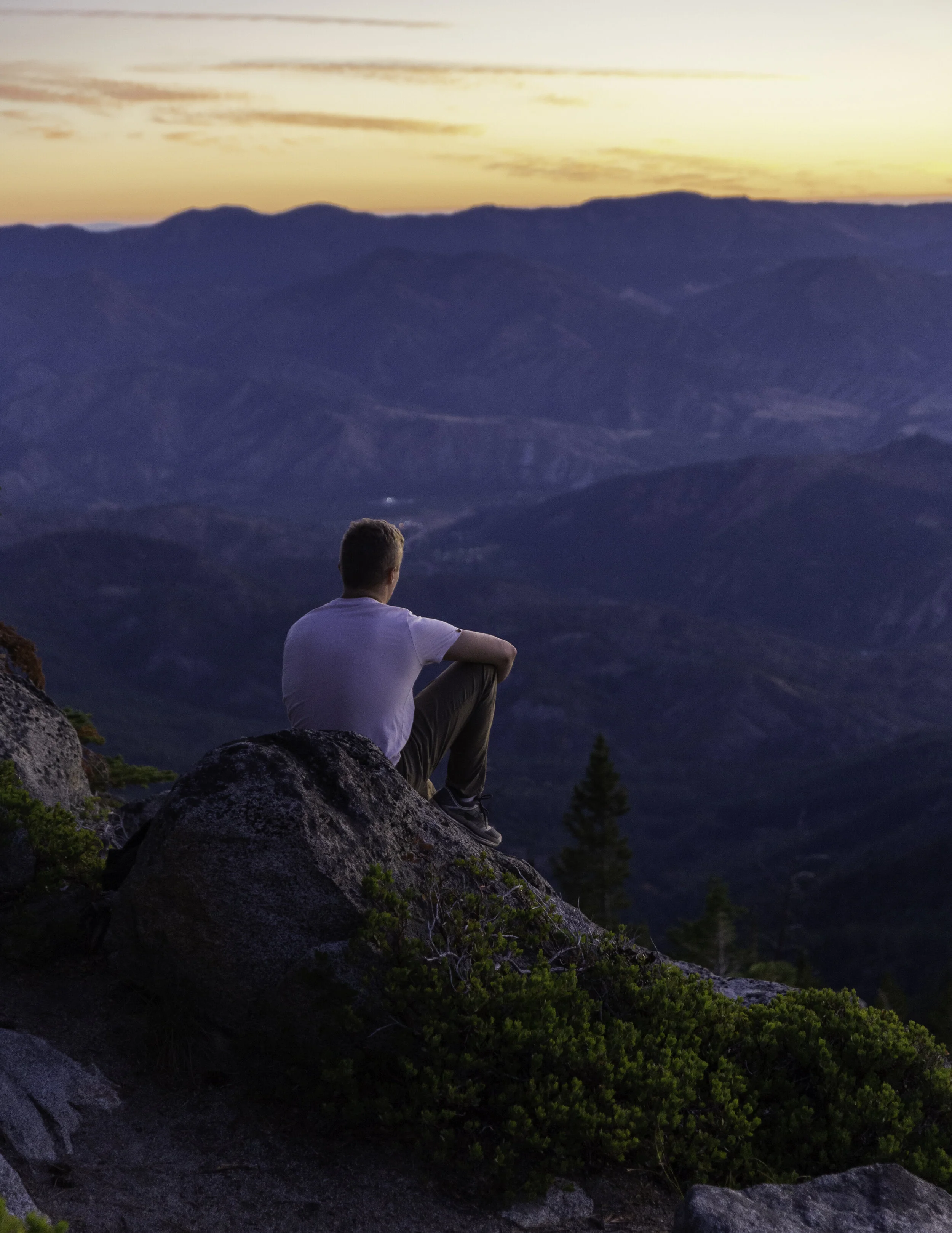 A man sitting on a rock overlooking the Wenatchee Valley at sunrise 