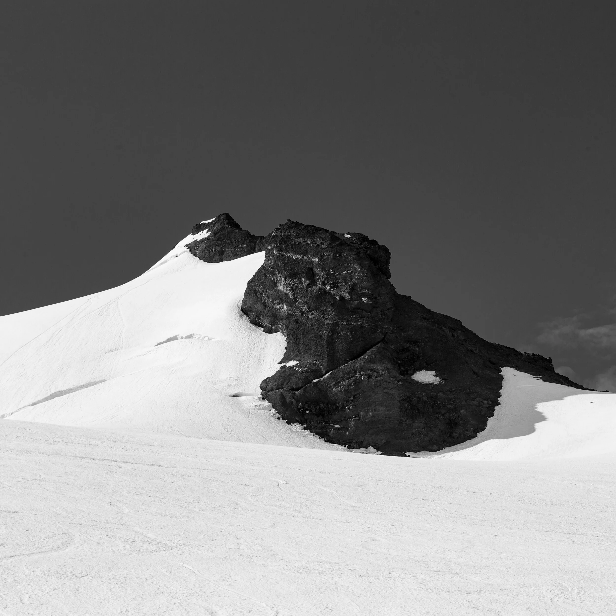 Black and white photo of a snow-covered mountain with dark rock formations