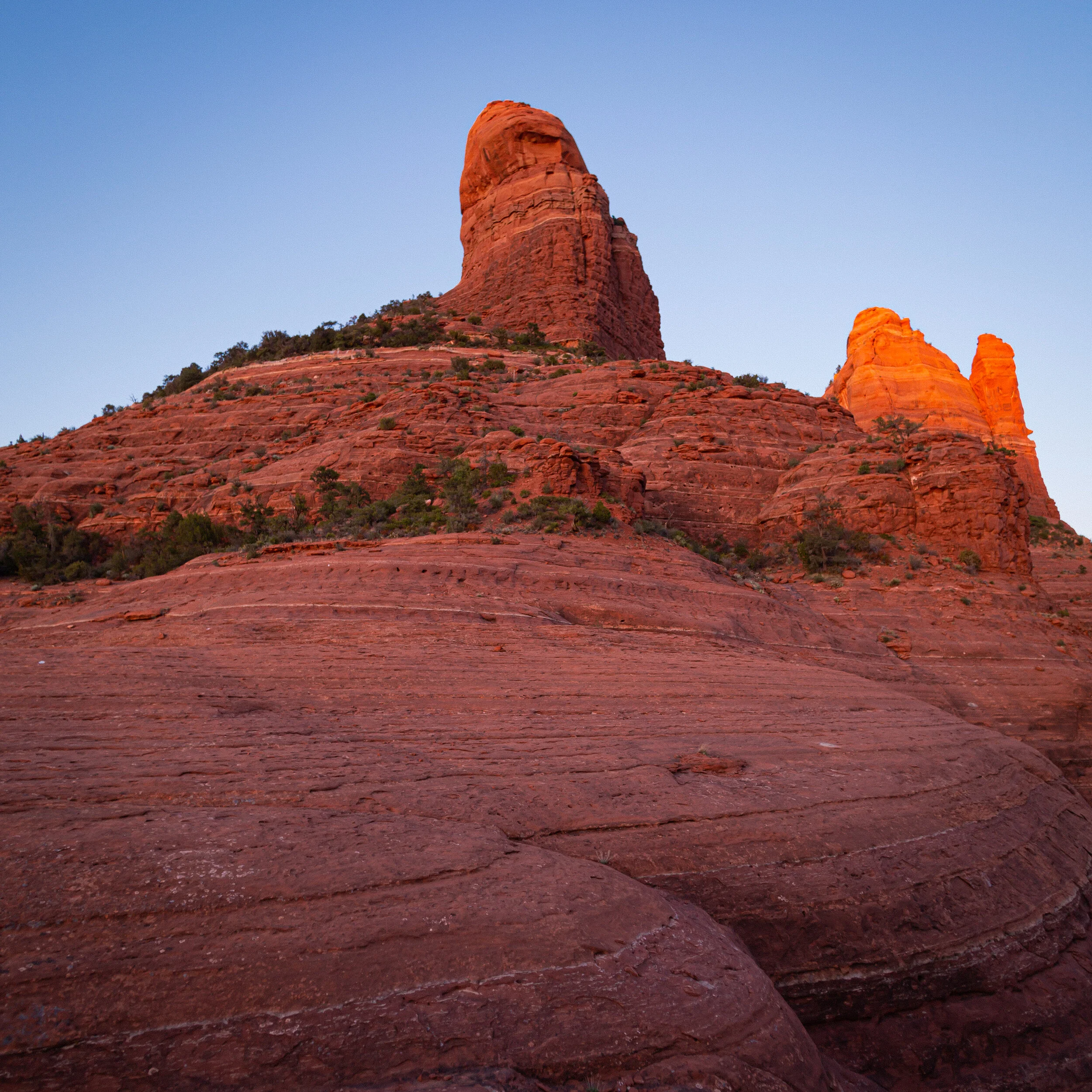 Red rock formations and spires in a desert landscape, likely in Sedona, Arizona, under a clear sky.