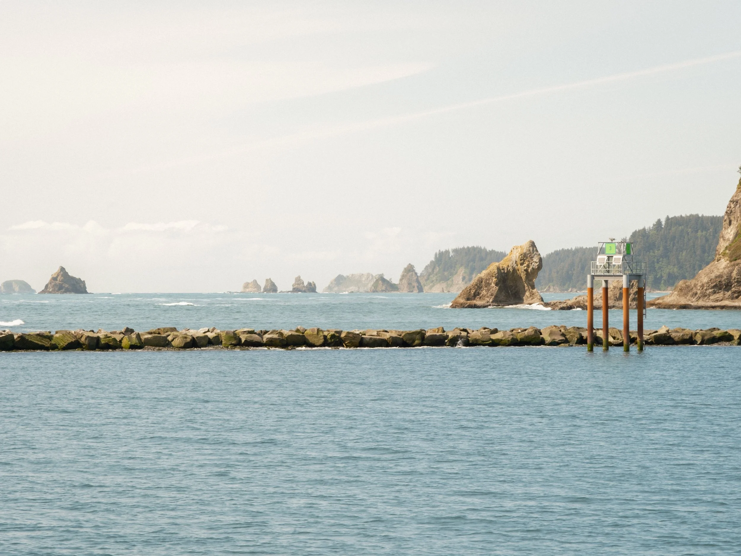 Ocean coastline with rocky islands and a small structure on stilts near the shore.