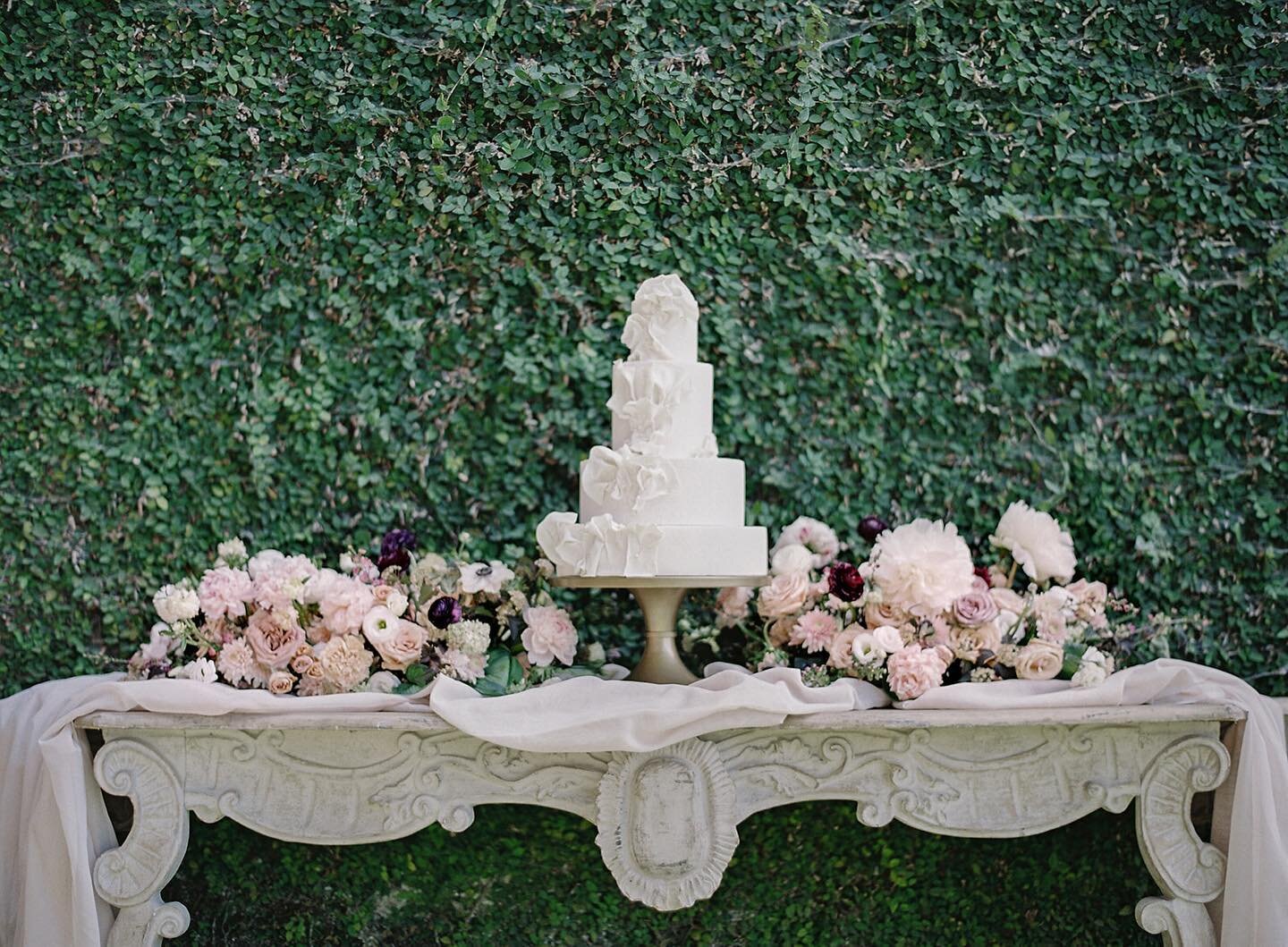 This delightful cake by @sweetrhi_ has us dreaming the sweetest dreams! We love how our Rose Clay hand-dyed tapestries are paired with @isibealstudio&rsquo;s romantic florals on this elegant table from @oohevents. And that glorious garden hedge at @m