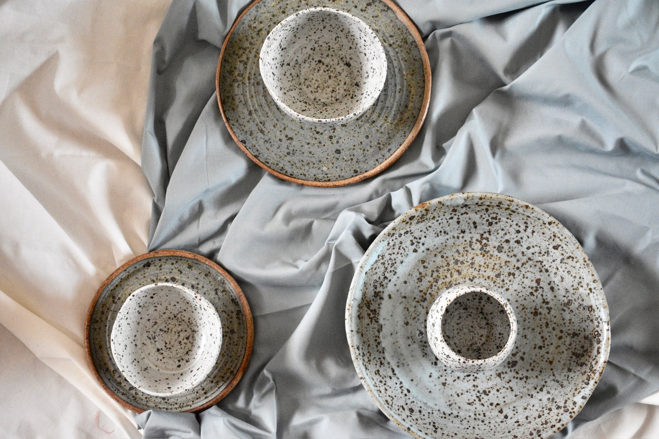 Side plate, dinner plate, and serving dish with three small footed bowls, reduction fired stoneware