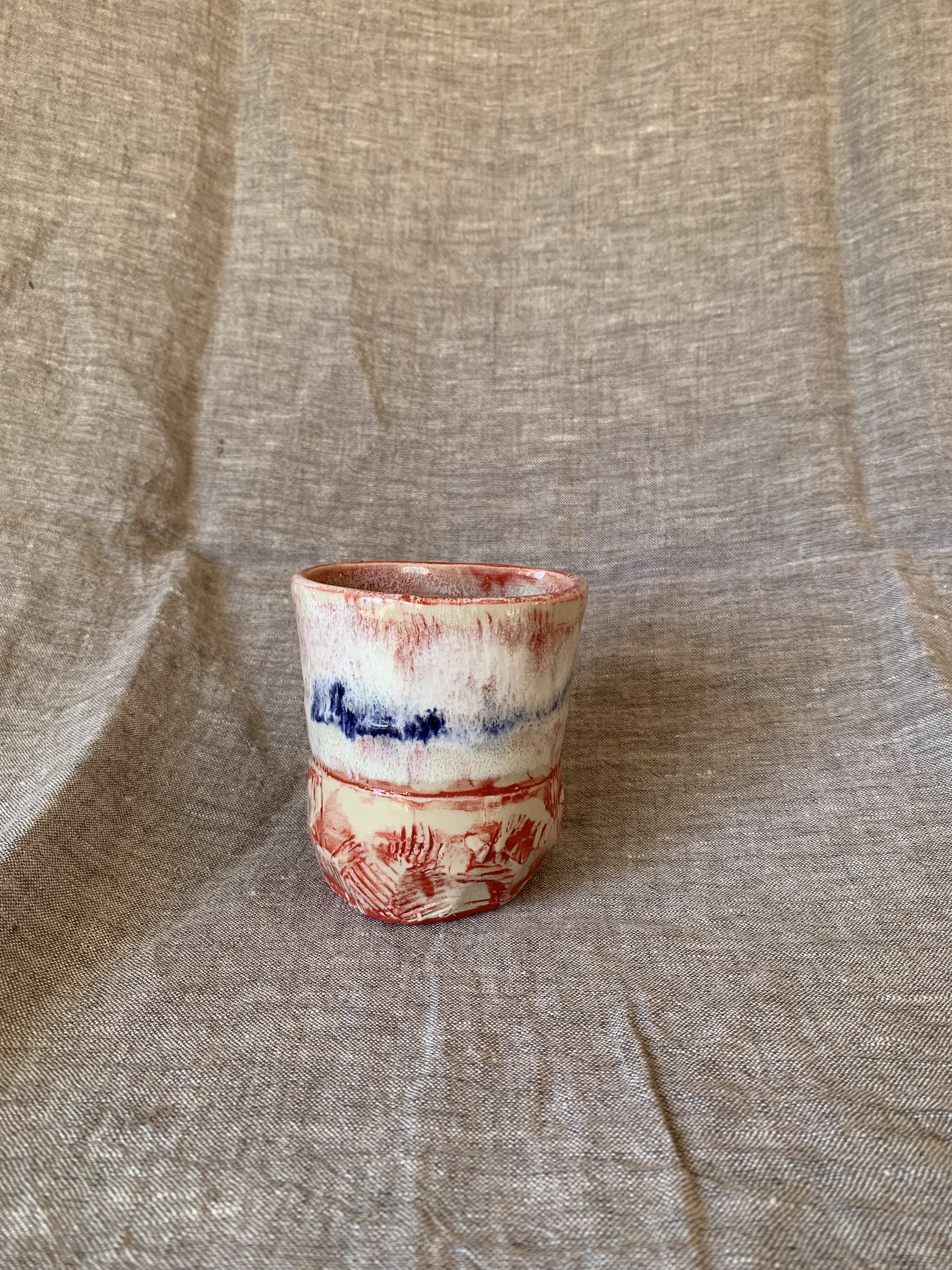 Small carved stoneware tumbler decorated with red slip and cobalt oxide