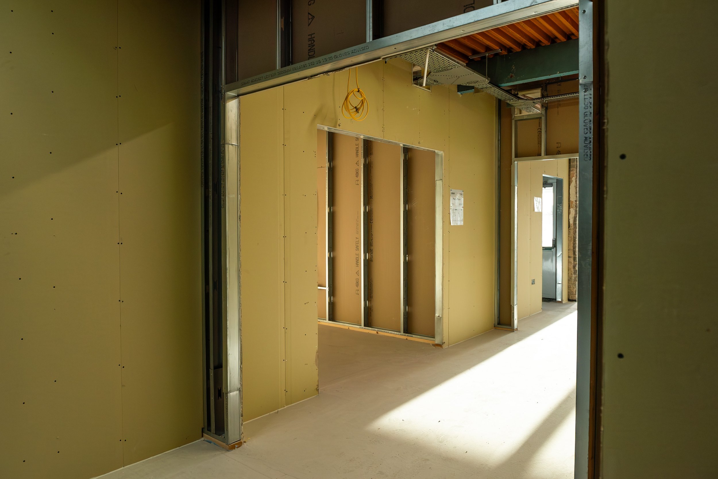 Partitions framing a large activity space beneath the original ribbed concrete ceiling of the former Aust Services