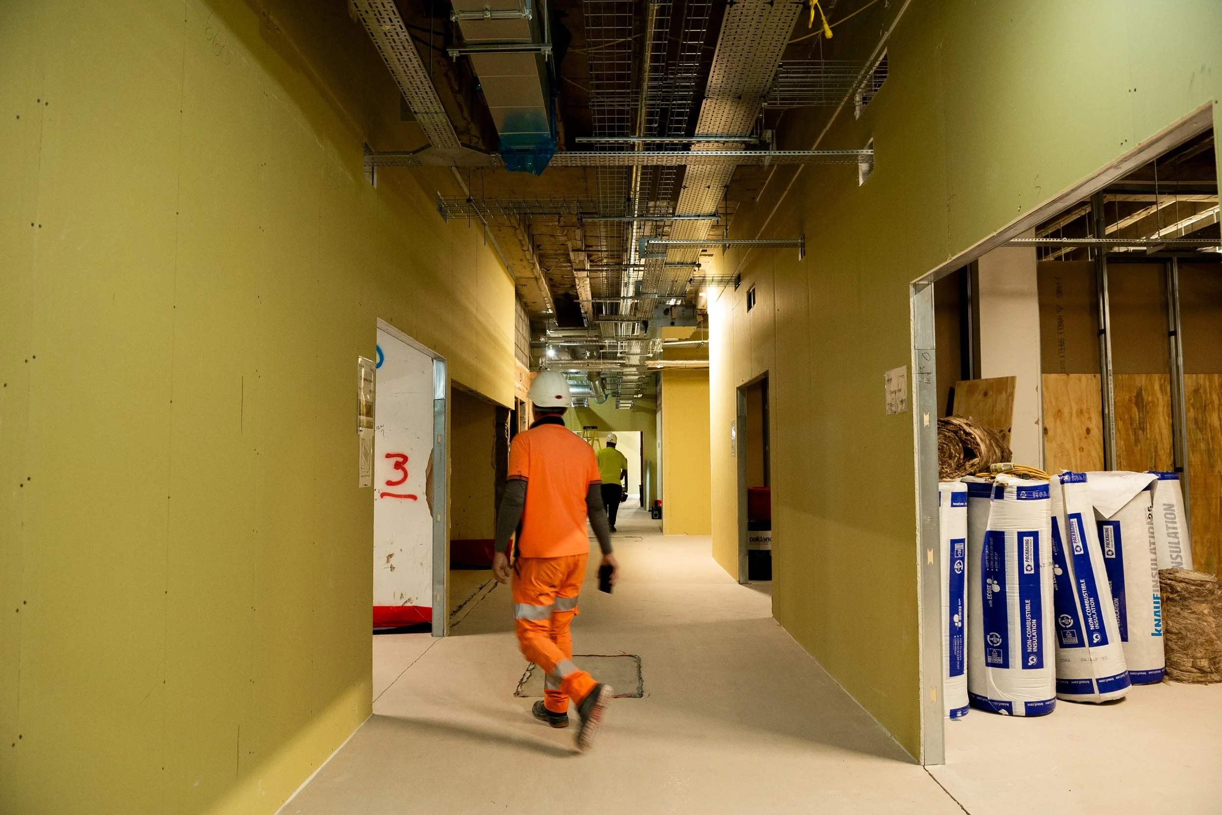Partitions framing a large activity space beneath the original ribbed concrete ceiling of the former Aust Services
