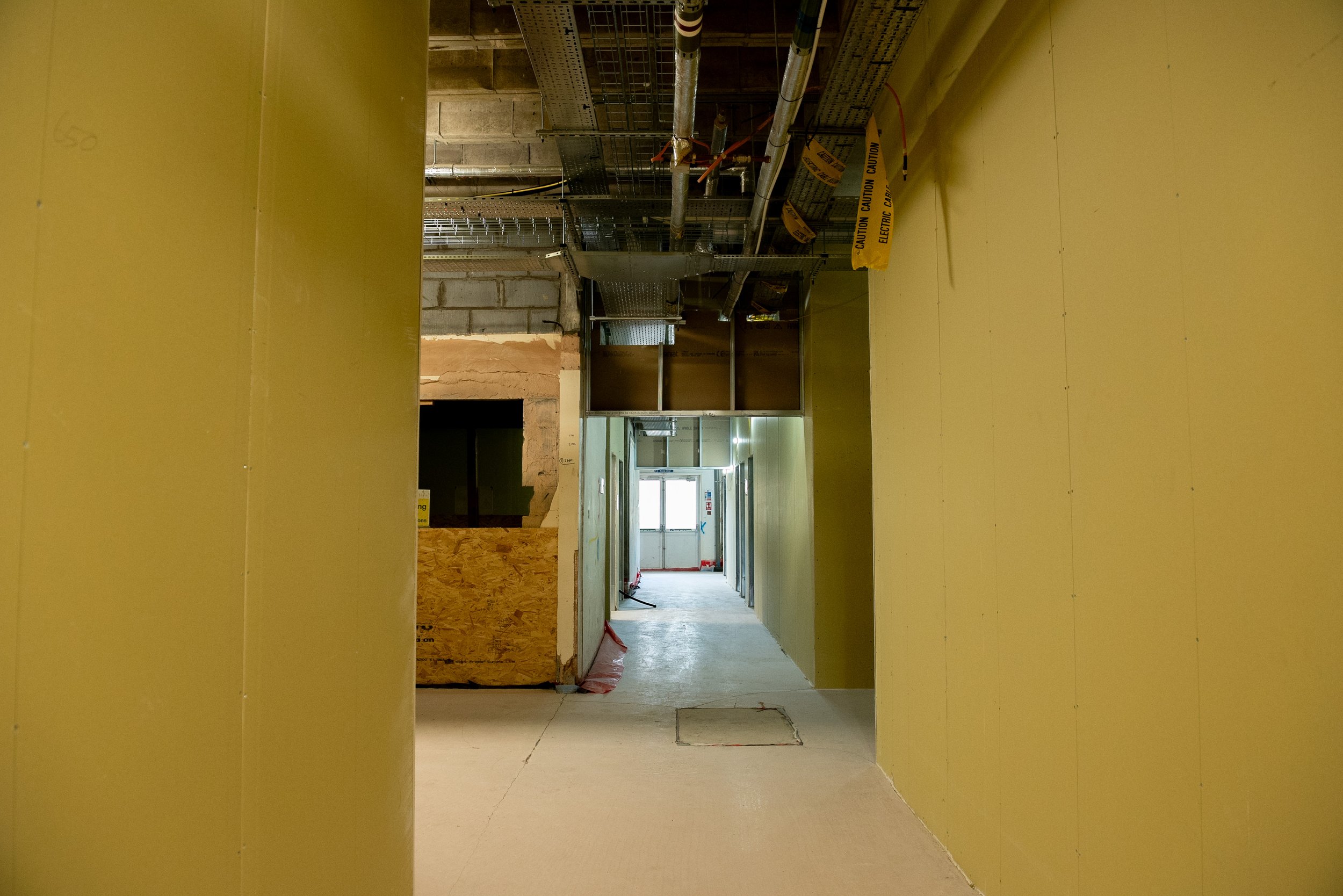 Partitions framing a large activity space beneath the original ribbed concrete ceiling of the former Aust Services