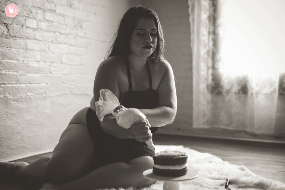 Black-and-white-photo-of-nude-woman-in-apron-icing-a-cake.jpeg