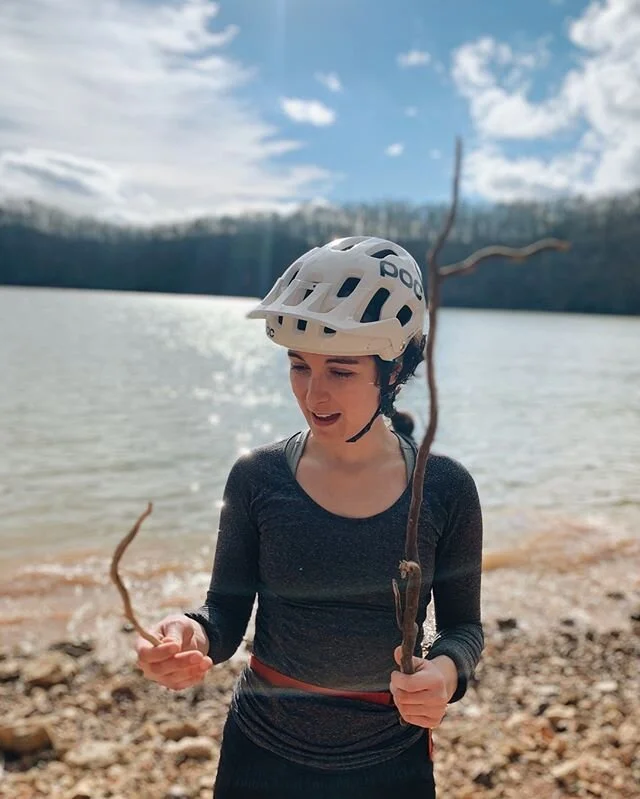 I stopped my birthday mountain bike ride to play with sticks and rocks by the lake. ☀️ The natural world has always fascinated me and for the first time, I find myself in a relationship with someone who — no matter how far or how fast we are going — will stop at a moment’s notice so I can look at tiny pine cones or find the nicest piece of sun-bleached wood to admire. 
Not just on my birthday, but everyday. We can pull over the car so I can forage some random plant from the side of the road. I can have no pockets but ask if he’ll carry rocks home for me. And, he does. 
I’ve known my entire life that I wasn’t meant to be alone. I am very independent and fiercely protect my individuality, but I honestly don’t want to be alone for longer than a day. 🤷🏻‍♀️ So, my life has been a series of friendships, groups, relationships, collaborations, partnerships, and chosen-family that have sometimes been incredible, or (unfortunately), have torn me down. 
Right now, after a week of being 27, I’m relishing in gratitude for the community of people around me. My partner, who loves me as I am (and for that very reason), my chosen family (you know who you are), my girlfriends - accountability partners, ambitious inspirations, always there for a phone call or a cup of coffee, and the community in Knoxville that welcomed this wandering St Petian with open arms. 
There is no better birthday present than to be surrounded by people who love you - openly, whole heartedly, honestly, and happily - and you all continue to bless me. 💓 📷 | @biker8585 who just gets me 😂