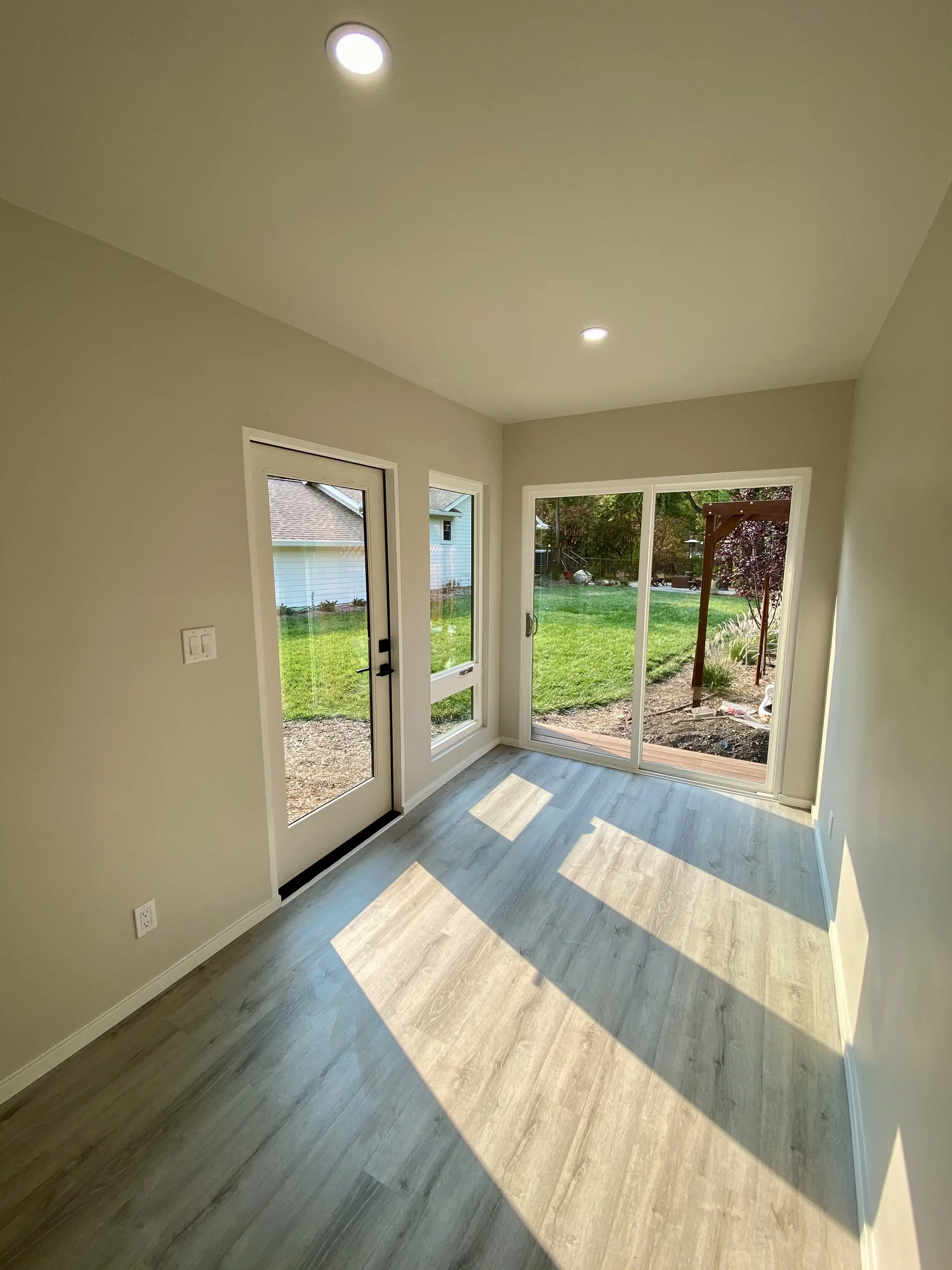 Bright interior of a Bay Modular ADU with light wood floors and glass doors to the backyard