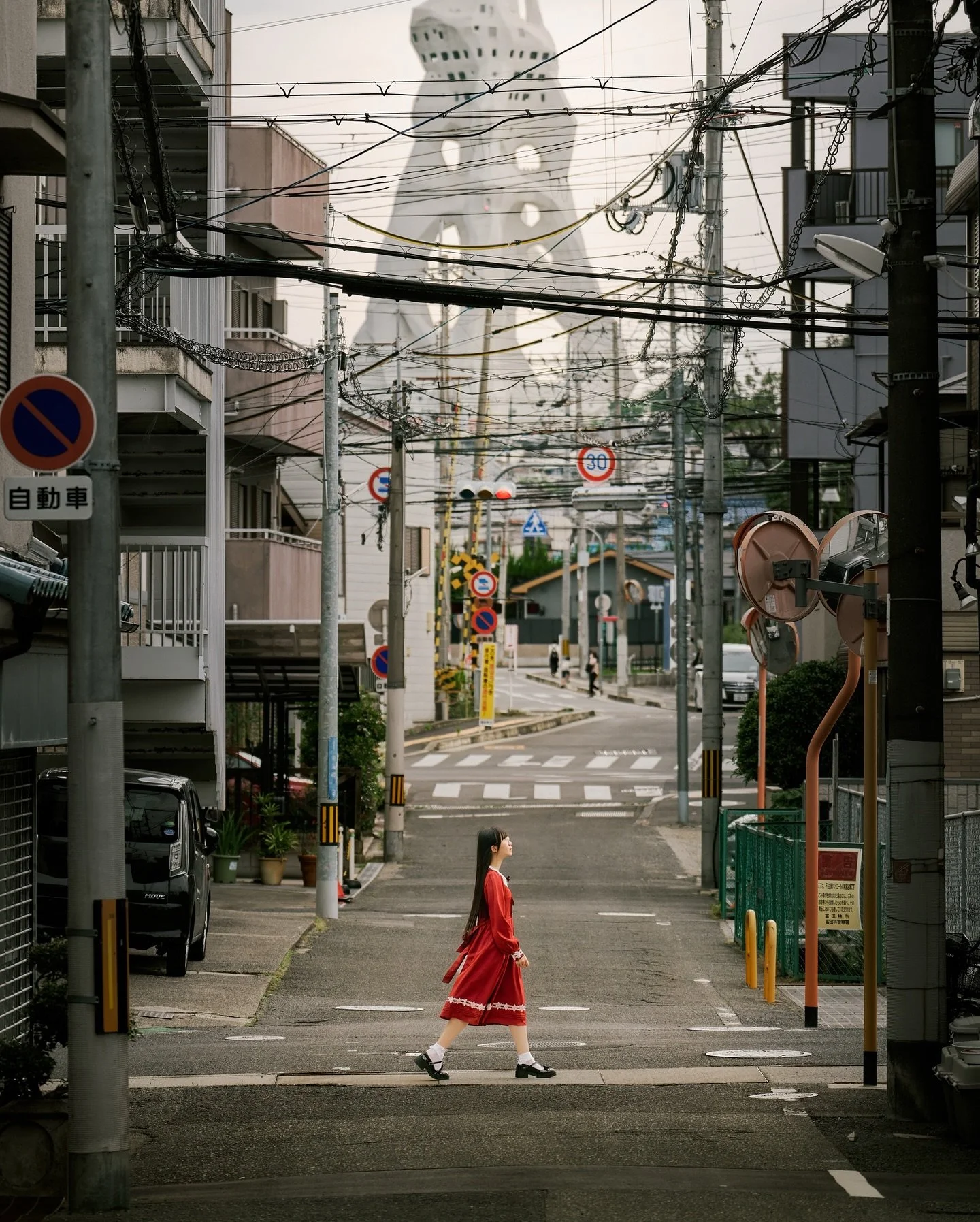 少女が一歩踏み出すたびに、世界はそっと現実からずれていく。
その先には、ただ静かに立ち尽くす白い塔があった。

少女每踏出一步，世界便悄悄偏離了現實。
在那前方的是一座靜靜佇立著的純白之塔。

─────
📍 大阪・富田林 PLの塔
👤 @fairy15y
📷 Leica SL2 &times; SIGMA 70-200mm F2.8
引き寄せた塔、すれ違う少女。
遠くの未来が、路地の先に現れる。

.
.
.
#富田林 #PLの塔 #異世界 #現実か夢か #街スナップ
#少女写真 #構図