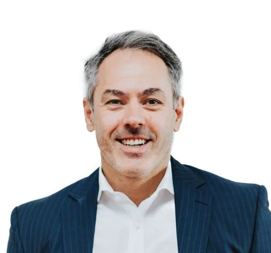 A smiling middle-aged man wearing a white shirt and a dark blue pinstripe suit against a plain white background.