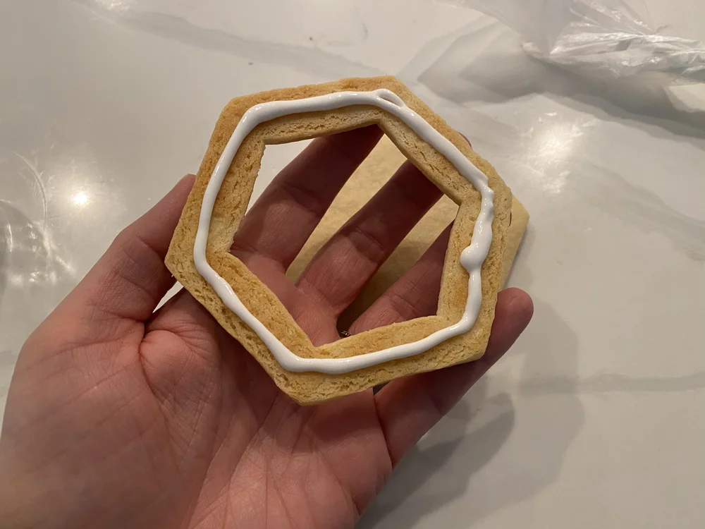  Pipe some royal icing on the bottom of one of the outline cookies.  The outlines may have morphed a little in baking. 