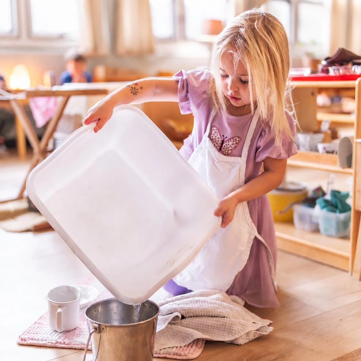 A child pouring water into a bucket.