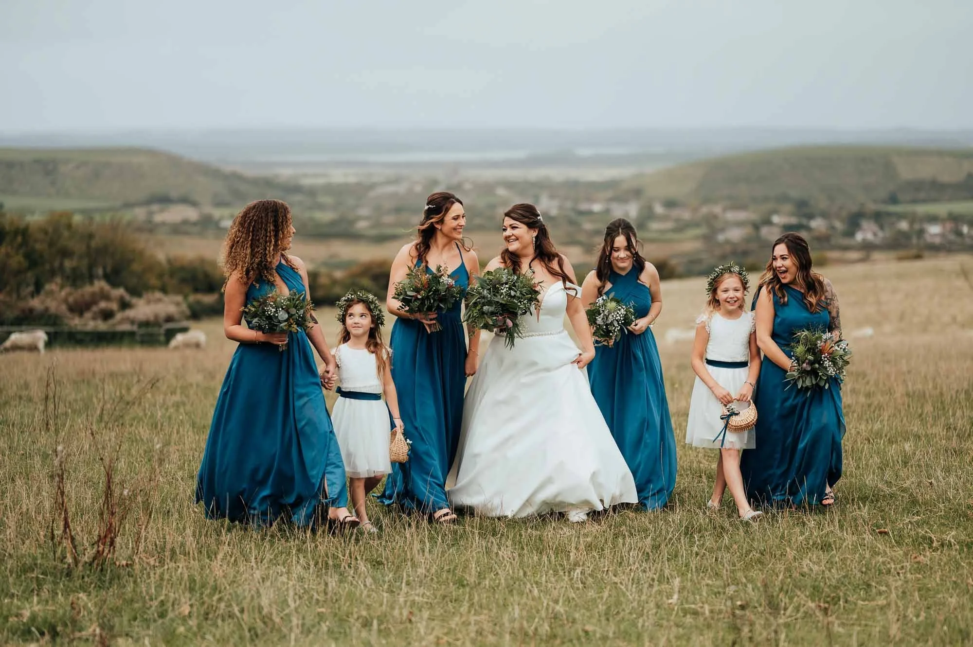  bride and bridesmaids walk through field in the purbeck hills of dorset  