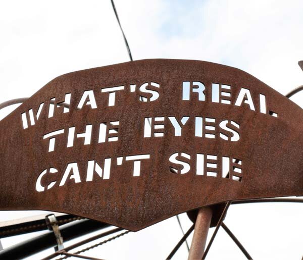  Rusted metal sign with the words “what’s real the eyes can’t see” cut into it. 