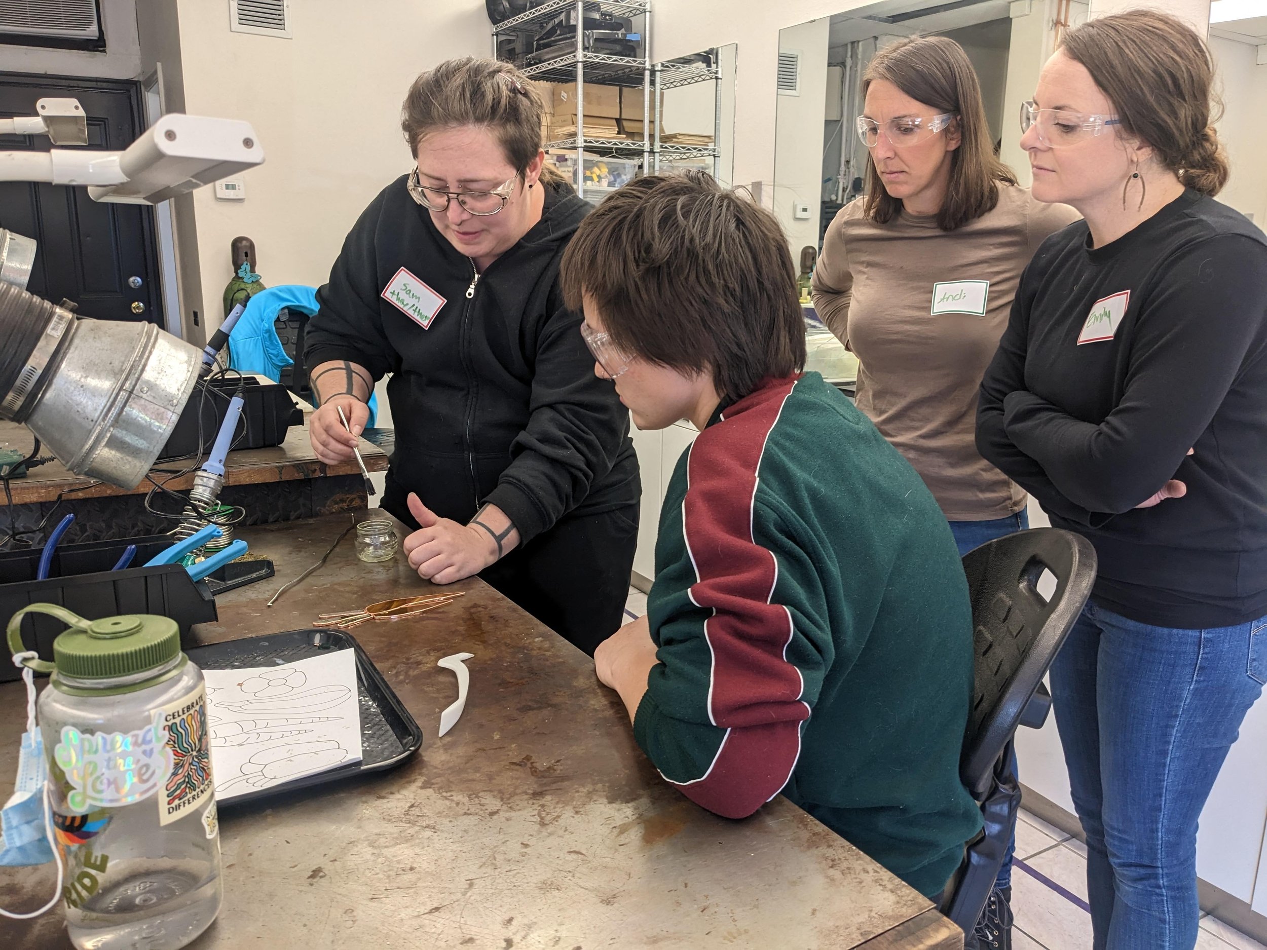  Photo of teacher demonstrating to three students how to make stained glass 