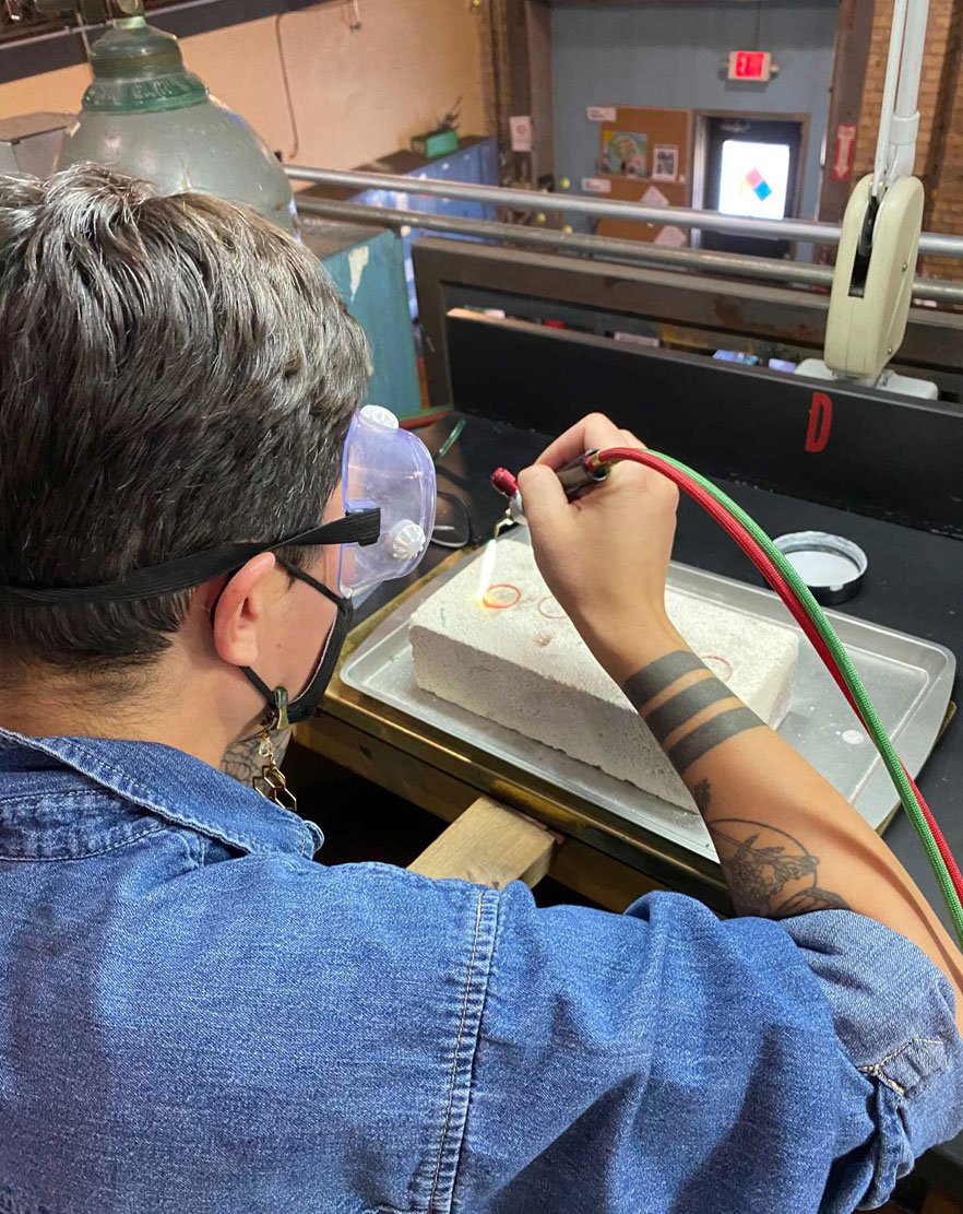  Photo of an artist using a jewelry torch to heat up metal 