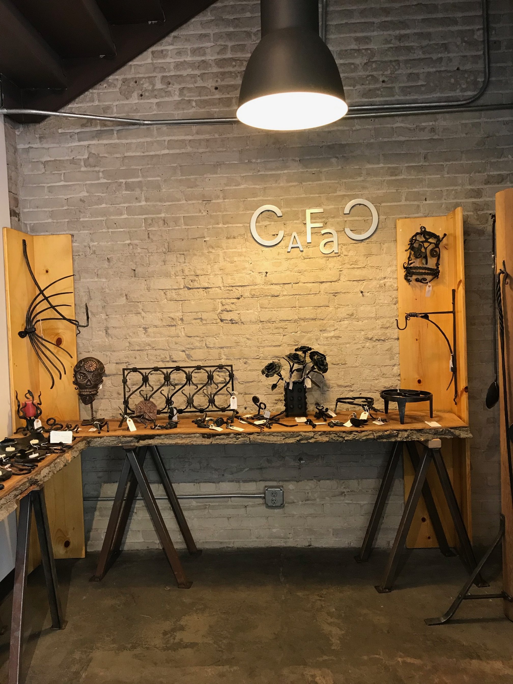 Photo of blacksmith products displayed on wooden boards on a wooden table.