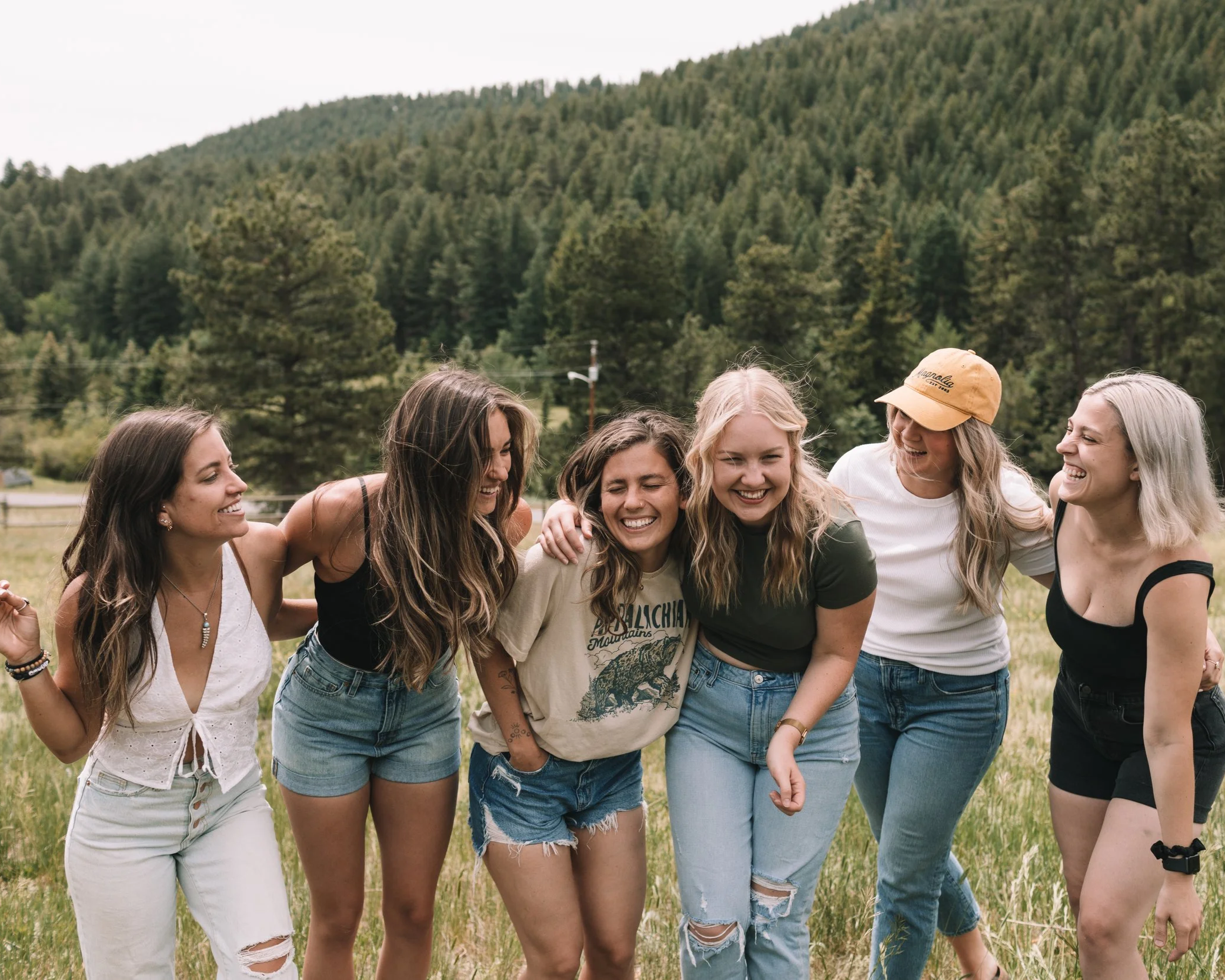 six young women smile and laugh together outdoors