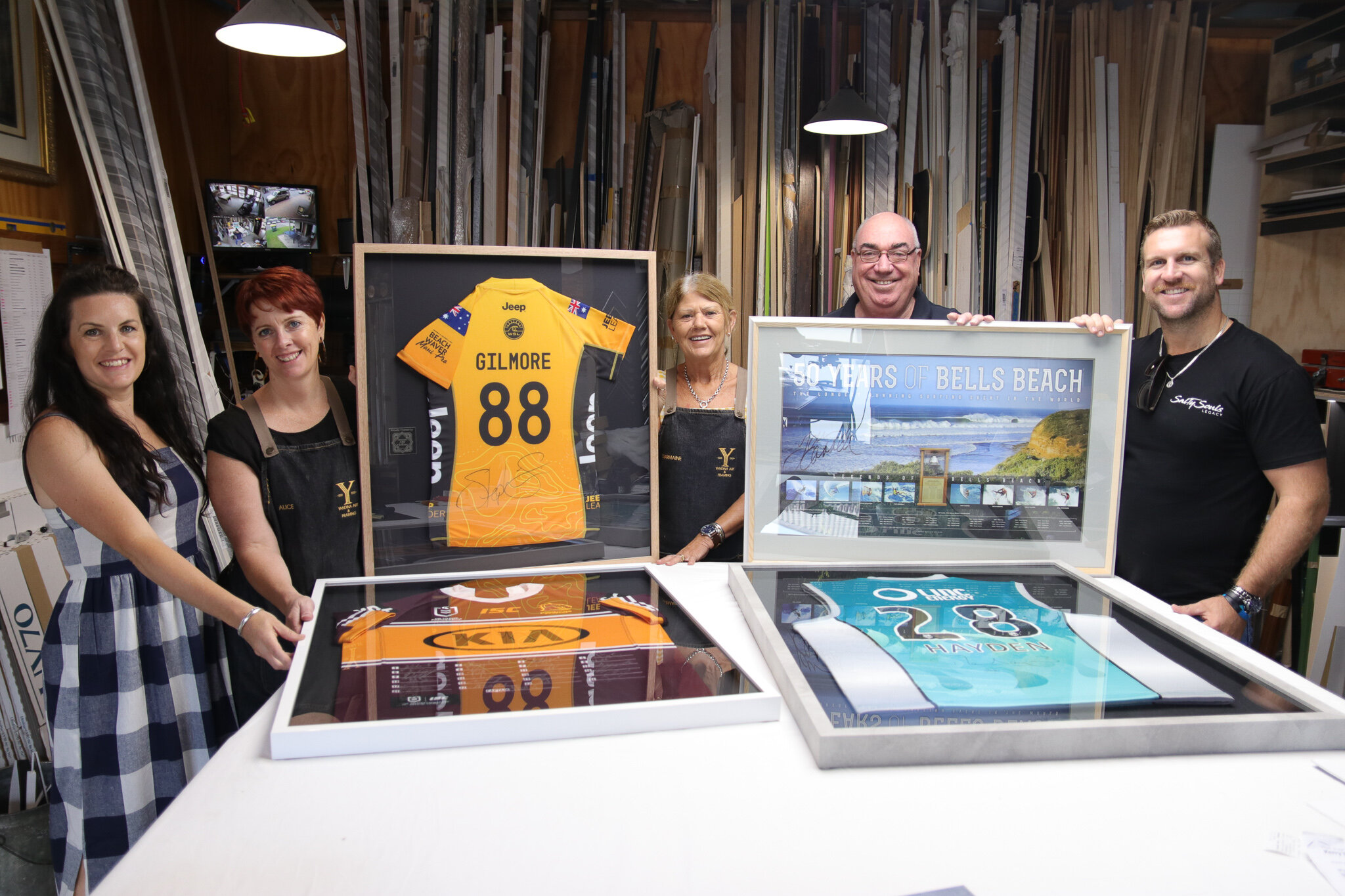 From left, Tania Maloup, Alice Graham, Charmaine Temple-Smith and Bill Gissane from Yandina Art &amp; Framing present the framed works to Kerry Smith from Salty Souls Legacy, an organisation which uses surf therapy to help vulnerable kids.